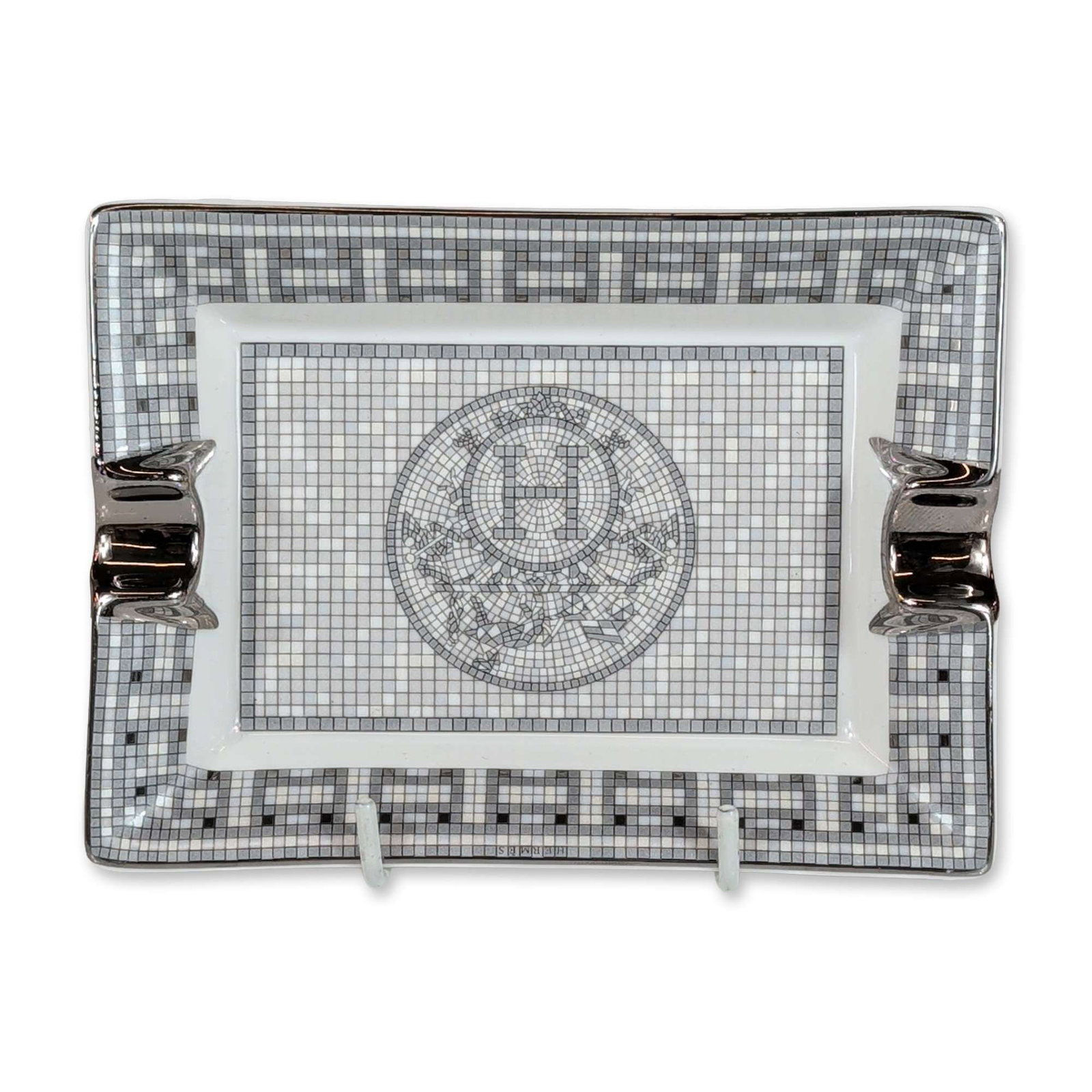 Hermes France Mosaique au 24 Platinum Porcelain Ashtray: Hermes porcelain ashtray in the Mosaique au 24 pattern with a rectangular form featuring a grayscale and platinum-tone mosaic tile motif centered by an H emblem. Includes two cigarette rests with a po