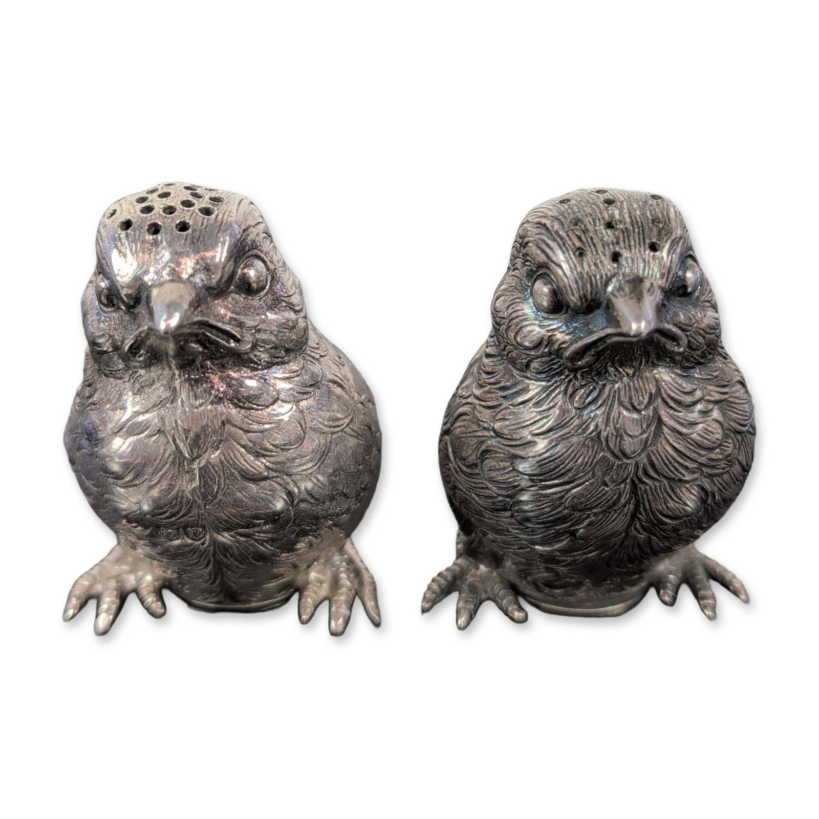 Pair of Antique Sterling Silver Owl Salt and Pepper Shakers: Antique sterling shakers crafted to resemble lifelike birds, each featuring intricately cast and chased plumage with detailed perching feet. The perforations for dispensing are cleverly placed at the 