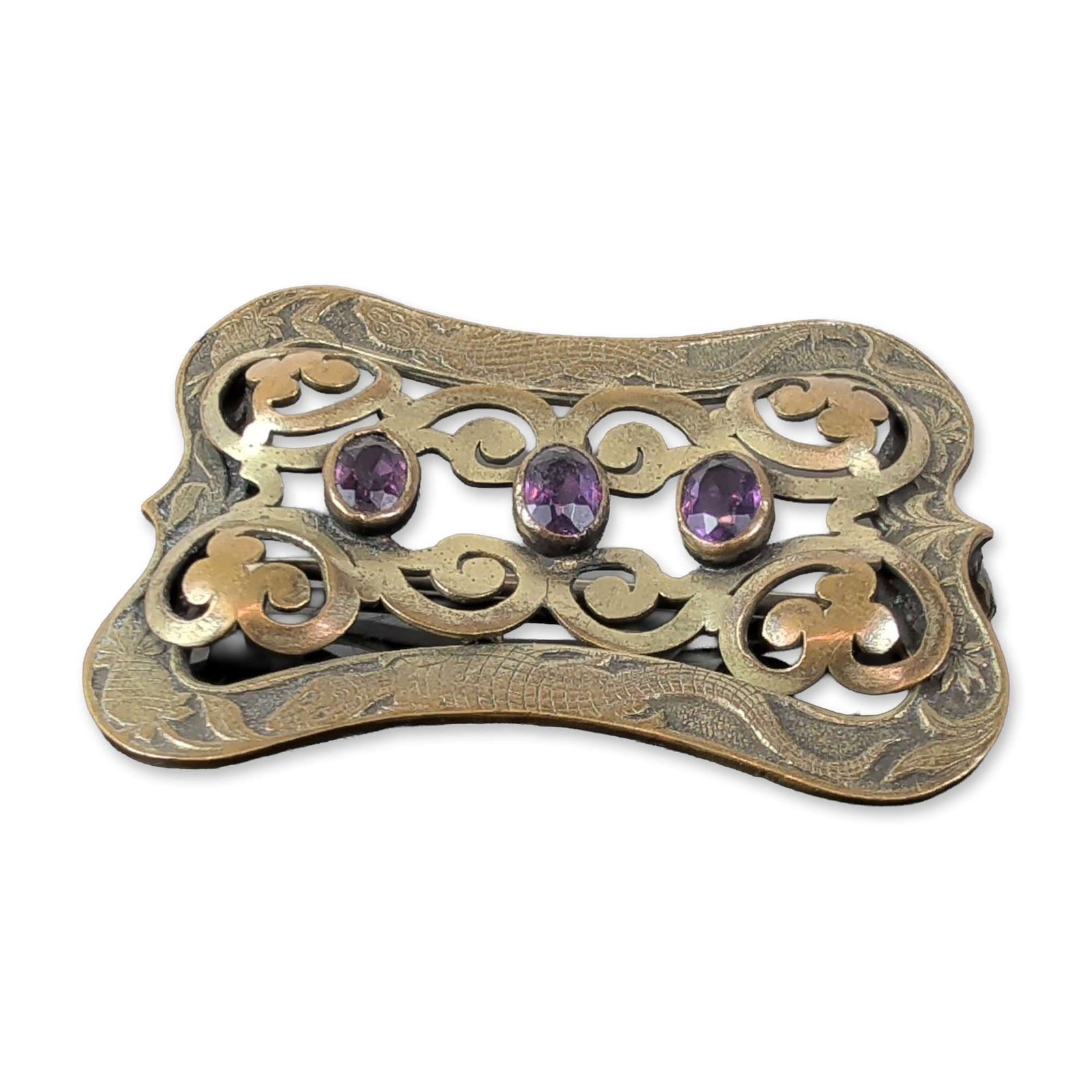 Art Nouveau Amethyst Glass Sash Brooch: Sash pin in two-tone gold-tone metal, featuring an openwork rectangular frame with scrolled filigree and etched foliate borders with alligator and pineapple motifs. The design incorporates four raised
