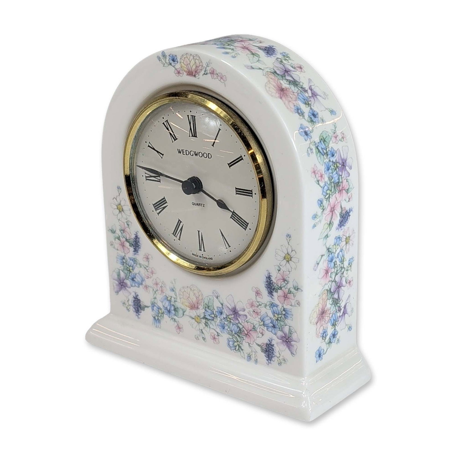 Wedgwood Angela Floral Bone China Mantel Clock: Wedgwood arched mantel clock in fine bone china, featuring the Angela pattern with lavender, blue, pink, and yellow floral sprays and green foliage. The circular white dial displays black Roman numera