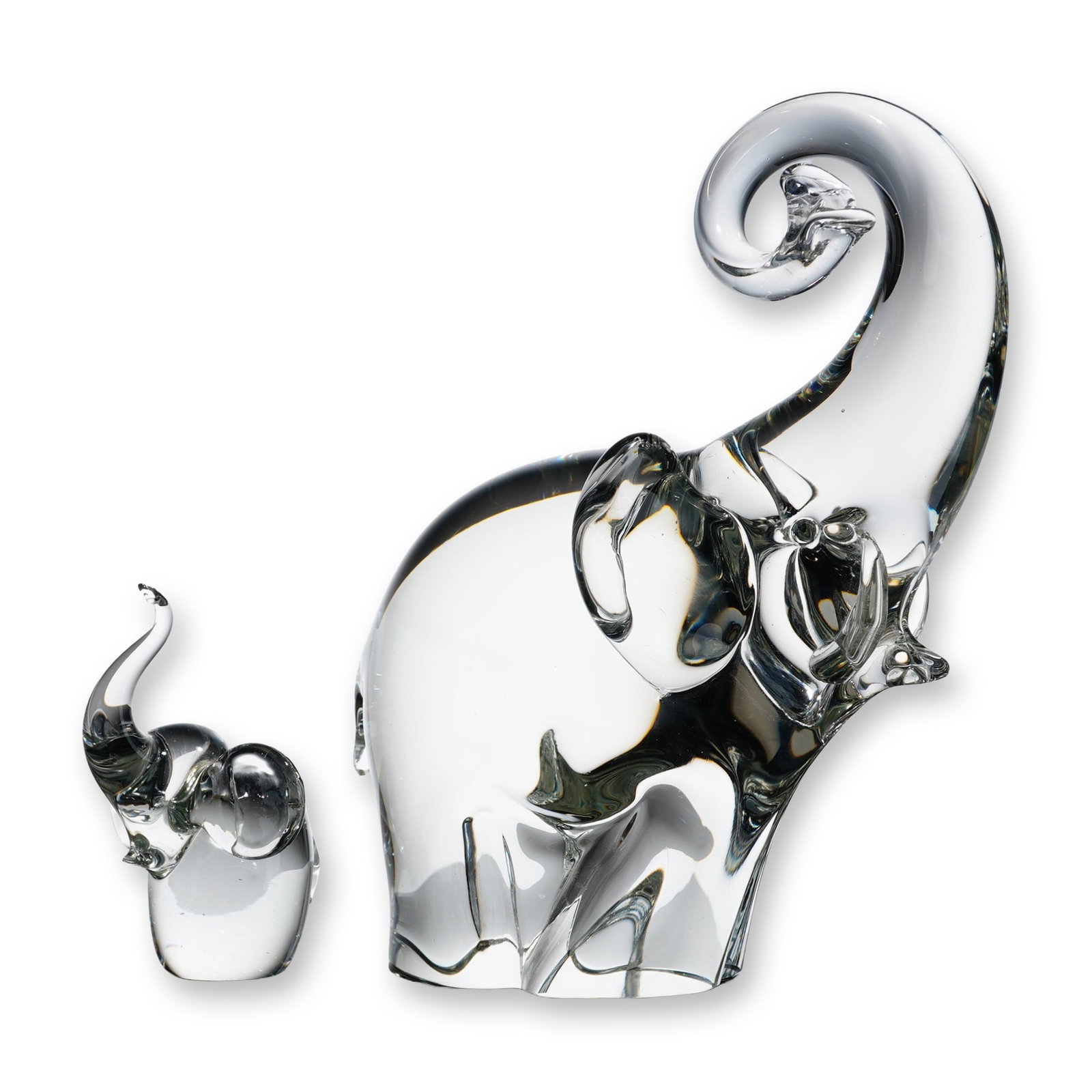 2pc Art Glass Elephant Figurines: Pair of heavy clear lead crystal elephant figurines, including an adult with a raised, curled trunk and a matching calf. Each feature smooth, rounded contours with stylized anatomical details and a po