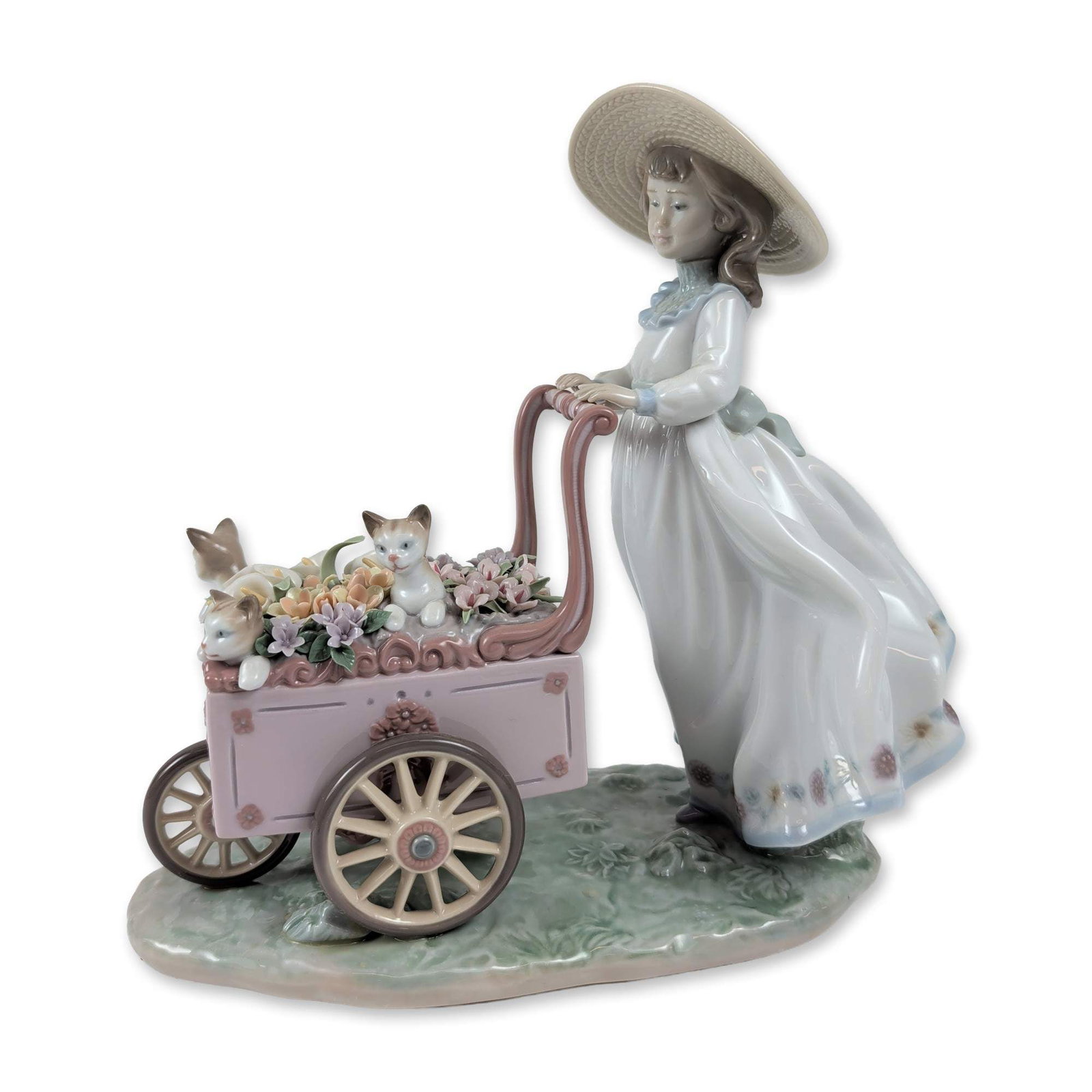 Lladro Porcelain Figurine, Kitty Cart 01006141: The Lladro glazed porcelain figurine, Kitty Cart (model 6141), designed by Regino Torrijos, beautifully portrays a young girl in a wide-brimmed straw hat pushing a delightful pink-and-white floral car
