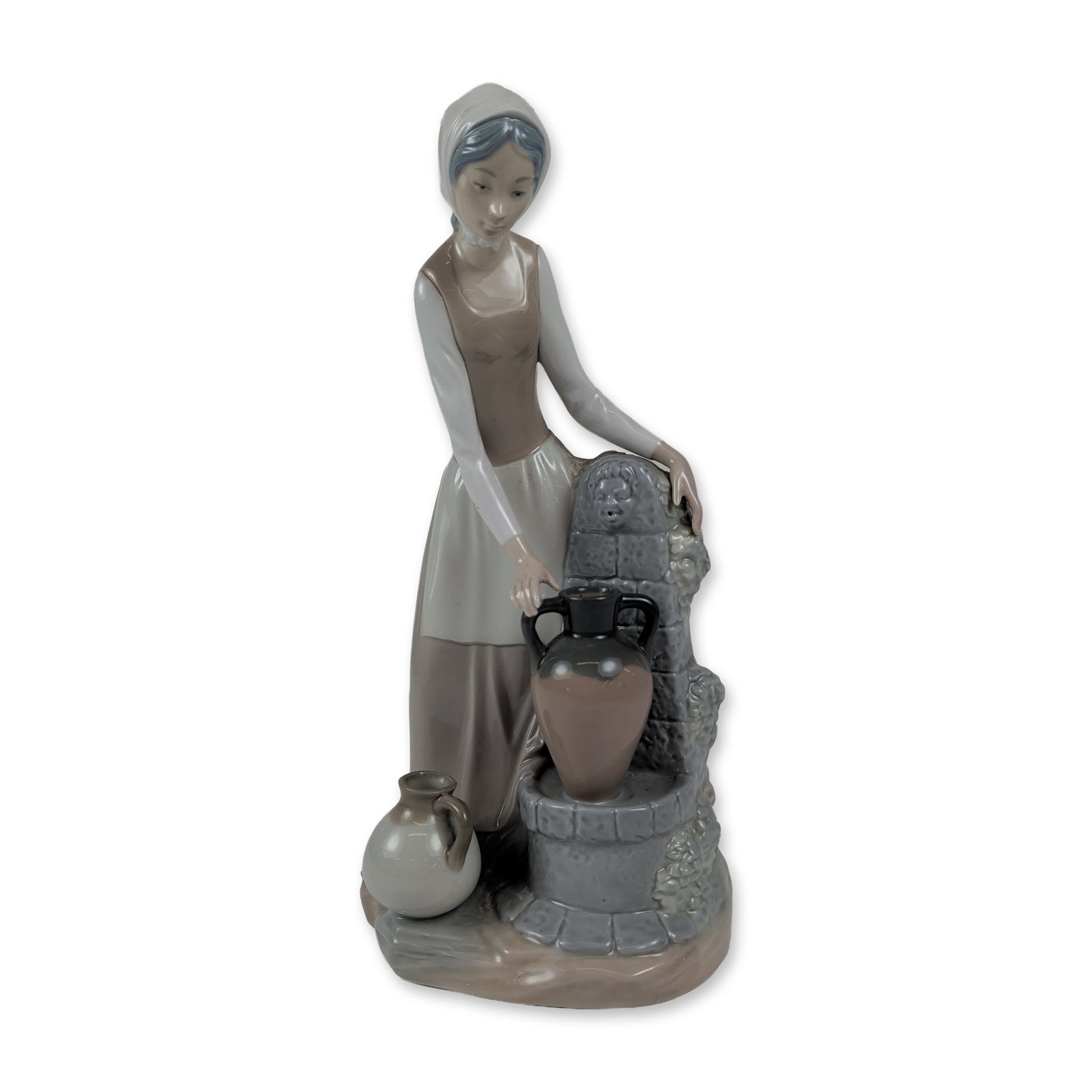 NAO by Lladro Porcelain Woman at Well Figurine: Glazed porcelain figurine depicting a young woman in rural attire featuring a headscarf, bodice, and long skirt. The figure is positioned beside a stone-walled well, resting one water jug on the ledge