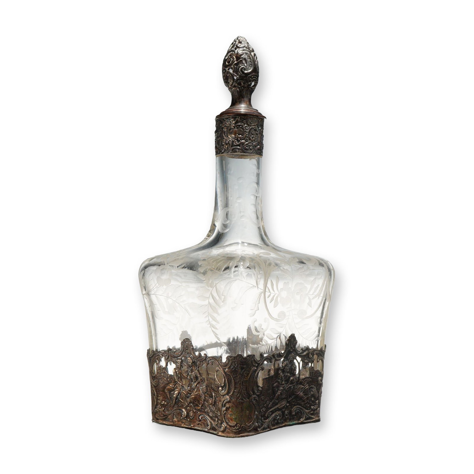 Italian 800 Silver Mounted Etched Glass Decanter with Stopper: This object is a clear glass decanter featuring etched decoration and a decorative metal sleeve. The glass body is decorated with wheel-engraved floral swags, foliate patterns, and bows. The item incl