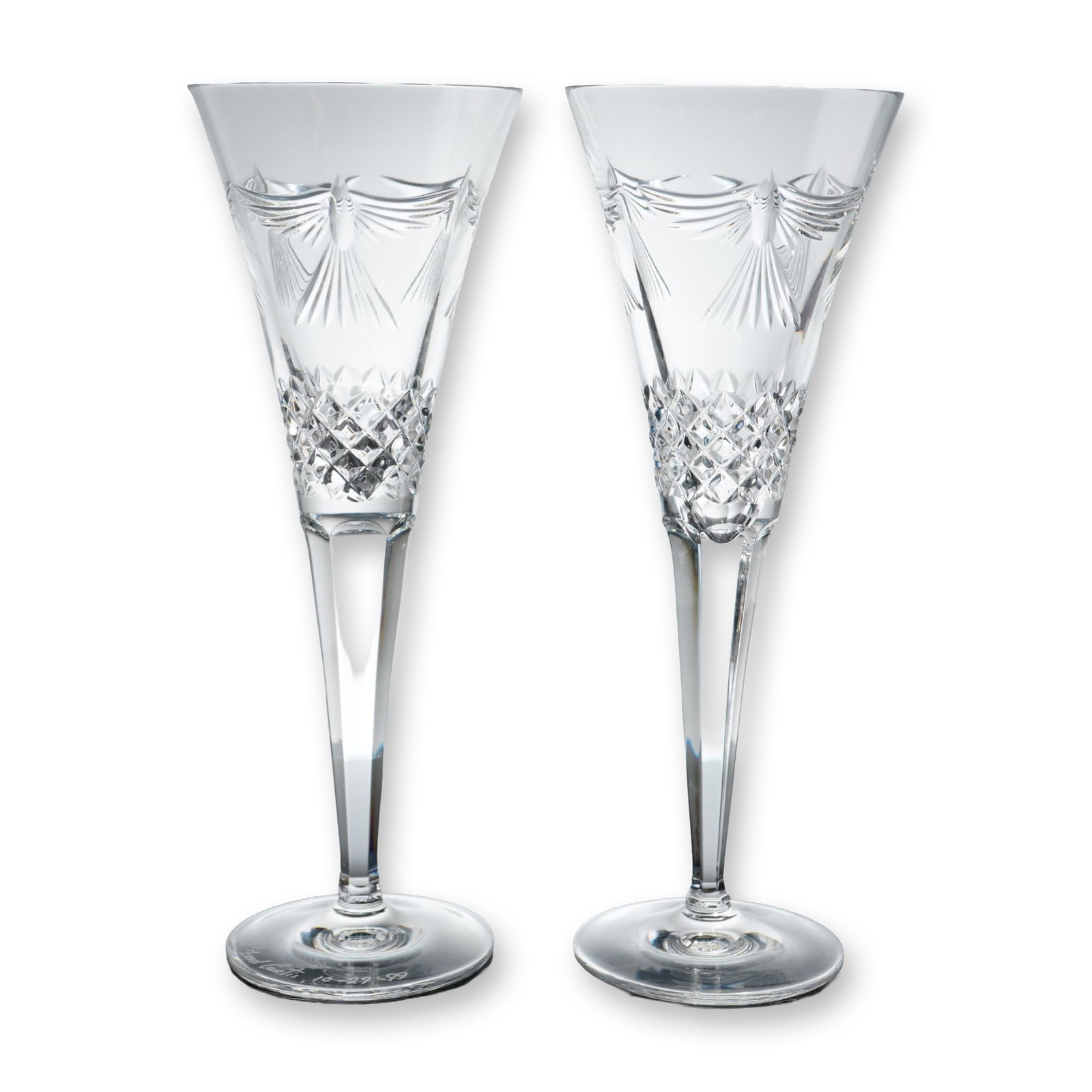 Pair of Waterford Fluted Champagne Millennium Series: Pair of lead crystal champagne toasting flutes from the Millennium series Collection. Tapered bowls feature the Peace dove motif with etched radiating lines above a band of deep diamond crisscross cut