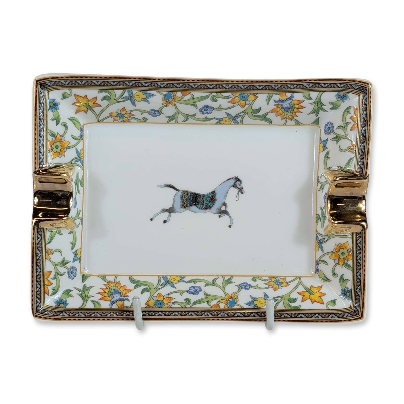 Hermes France Cheval d'Orient Porcelain Ashtray: Hermes porcelain ashtray in the Cheval d'Orient pattern. The rectangular piece features a central prancing horse motif with a polychrome decorative saddle, surrounded by a border of floral scrolls and