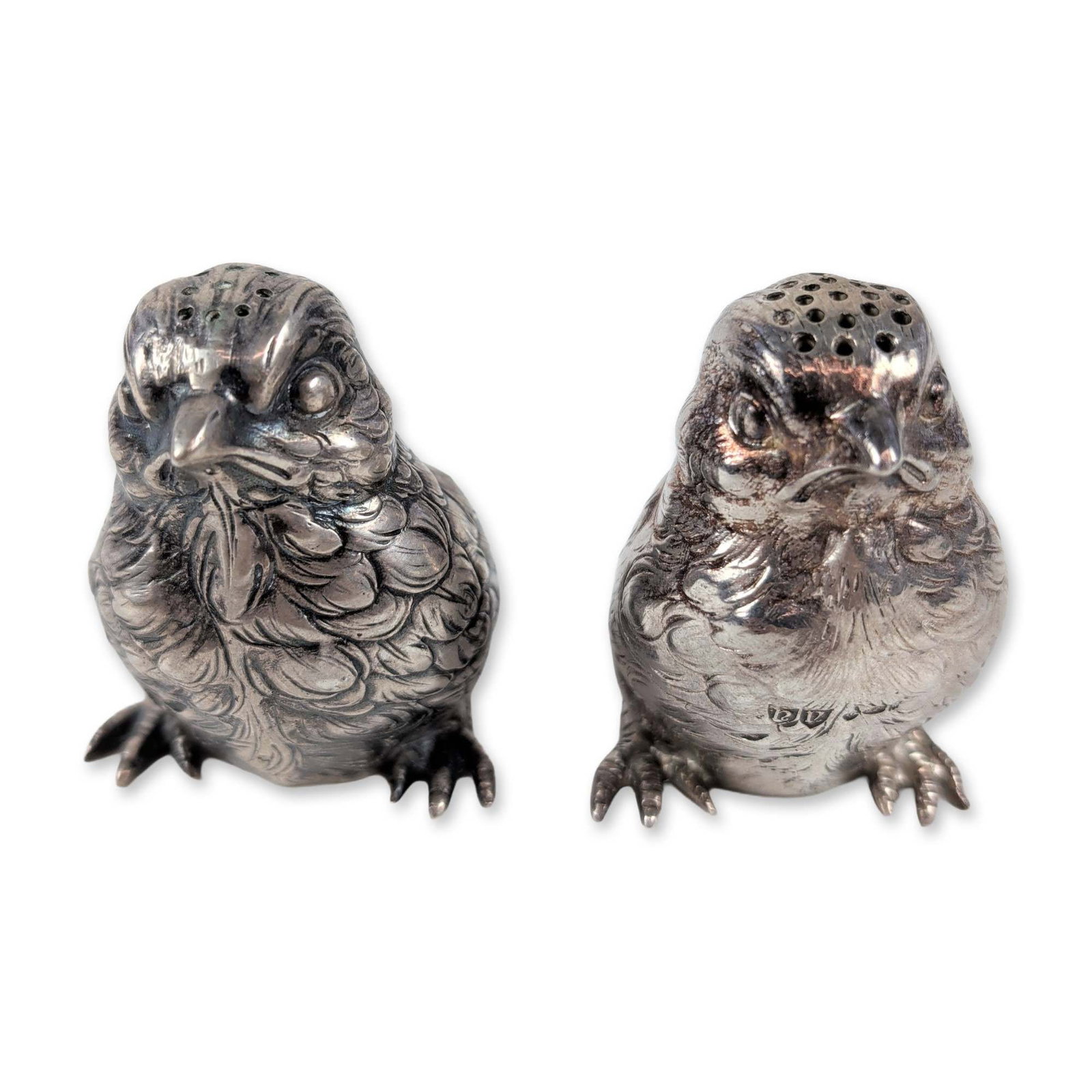 Pair of Sterling Silver Owl Salt and Pepper Shakers: British style salt and pepper shakers in sterling silver, modeled as owls with naturalistic cast feathering. Stamped with hallmarks including a lion passant, 925, and maker marks. Two pieces total. Te
