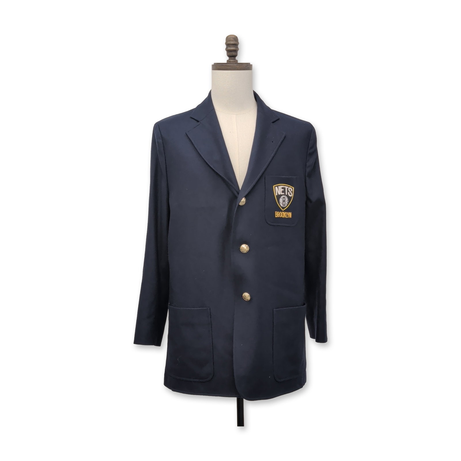 Rowing Blazers x NBA Brooklyn Nets Wool Navy Blazer: Rowing Blazers x NBA collection. 100% wool navy blue three-button blazer featuring notch lapels and three patch pockets. The left chest pocket is adorned with an embroidered Brooklyn Nets shield patch