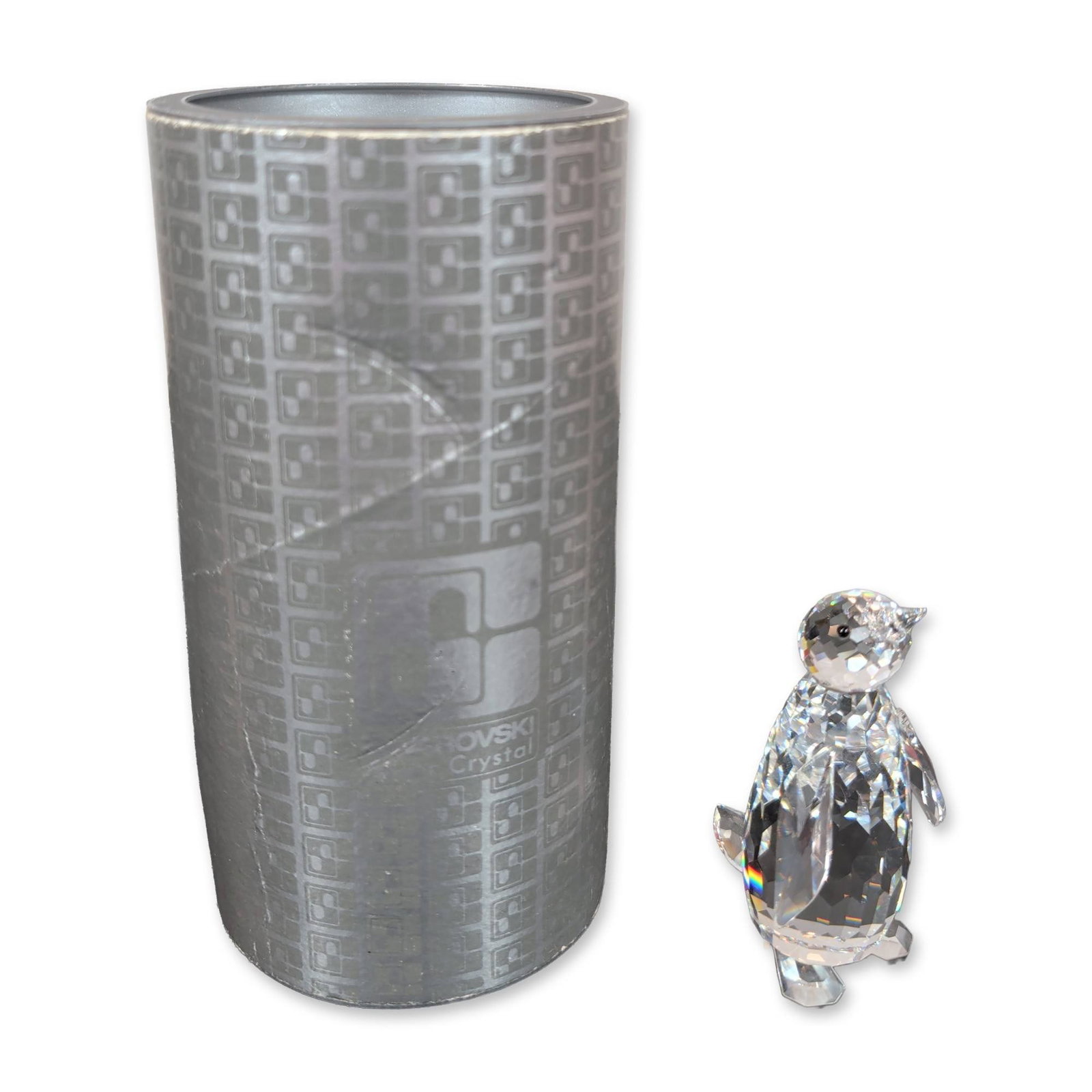 Swarovski Silver Crystal Penguin Figurine: The piece is constructed from faceted lead crystal, featuring a plump body with stylized side flippers and a smaller head with a pointed beak. Includes the original silver-toned cylindrical container 