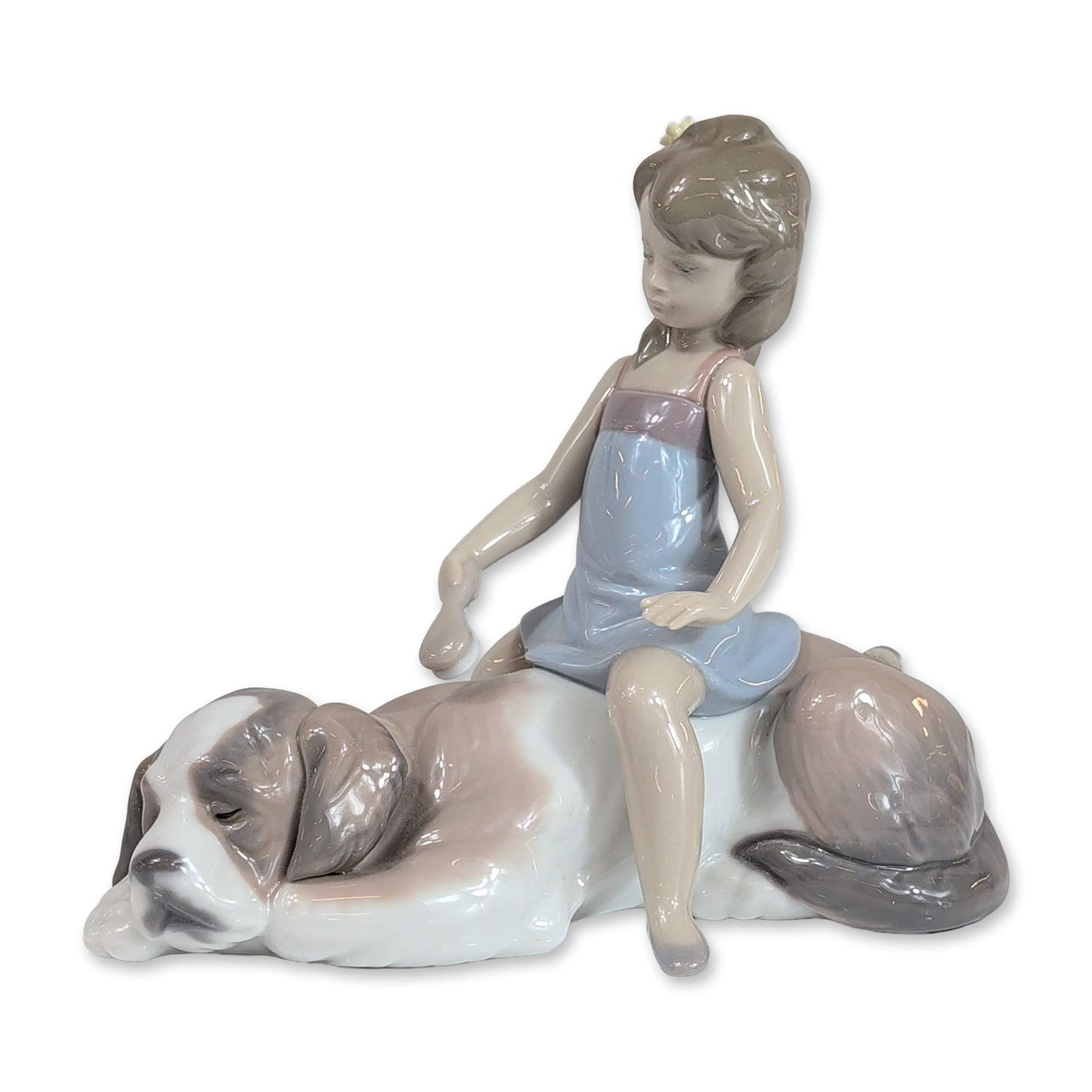 Lladro Contented Companion Glazed Porcelain Figurine: Lladro (Spain). Contented Companion porcelain figurine, model number 6229, depicting a young girl in a blue dress seated upon a reclining St. Bernard dog. The piece features a polychrome glaze in soft