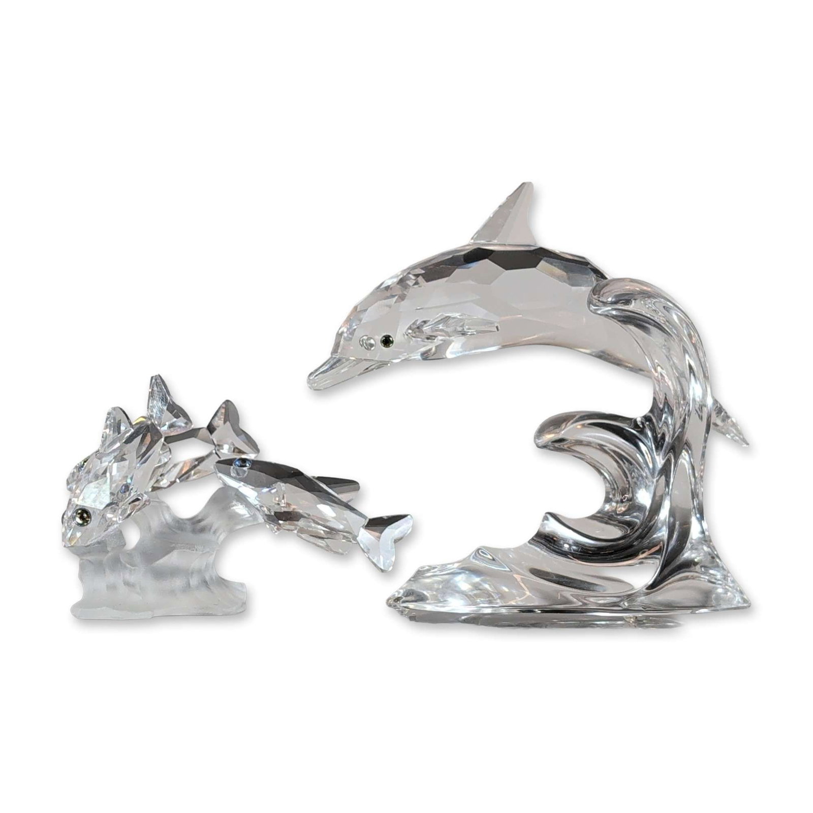 Two Swarovski Silver Crystal Aquatic Figurines: Swarovski Silver Crystal. Group of two aquatic figurines in lead crystal, featuring a school of fish and a leaping dolphin. The fish figurine depicts three clear faceted fish with dark bead eyes swimm