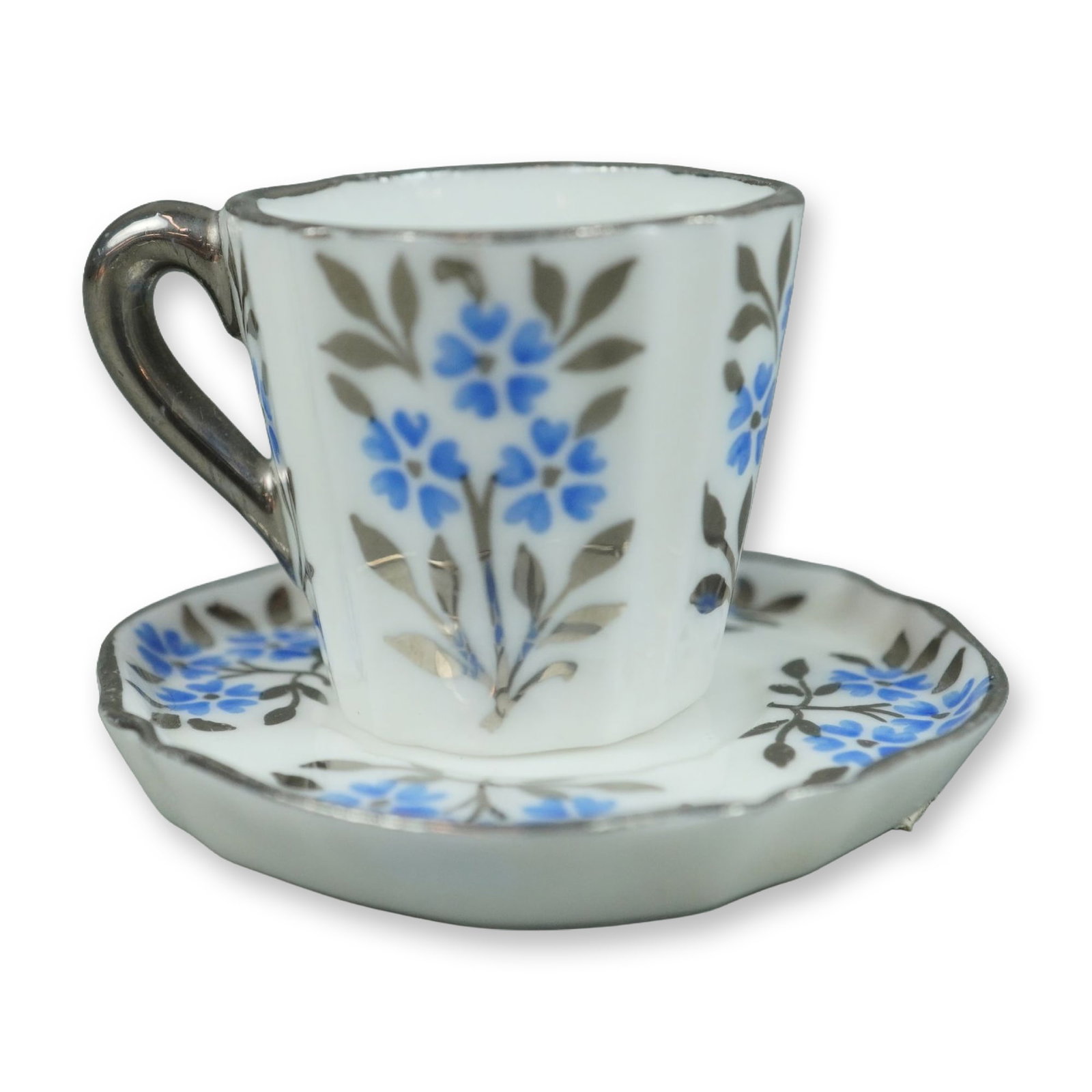 Wedgwood Bone China Miniature Teacup and Saucer in Silver Luster Forget-Me-Not Pattern: This is a miniature bone china teacup and saucer set produced by Wedgwood in England. The cup features a fluted or paneled body with a C-scroll handle, and the saucer has a matching lobed and scallope