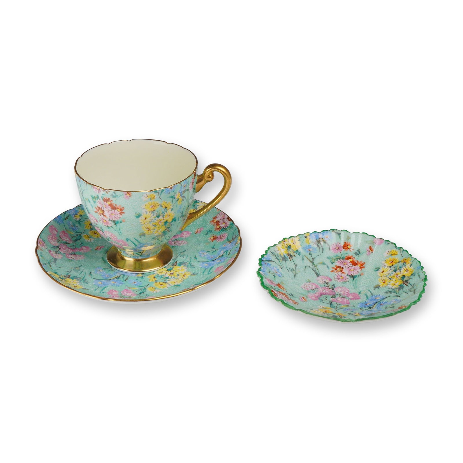 3pc Shelley Bone China Tea Trio, Melody: This lot features three pieces of Shelley fine bone china in the Melody chintz pattern, manufactured in England. The group includes a footed teacup with an ornate handle, a coordinating saucer, and a 