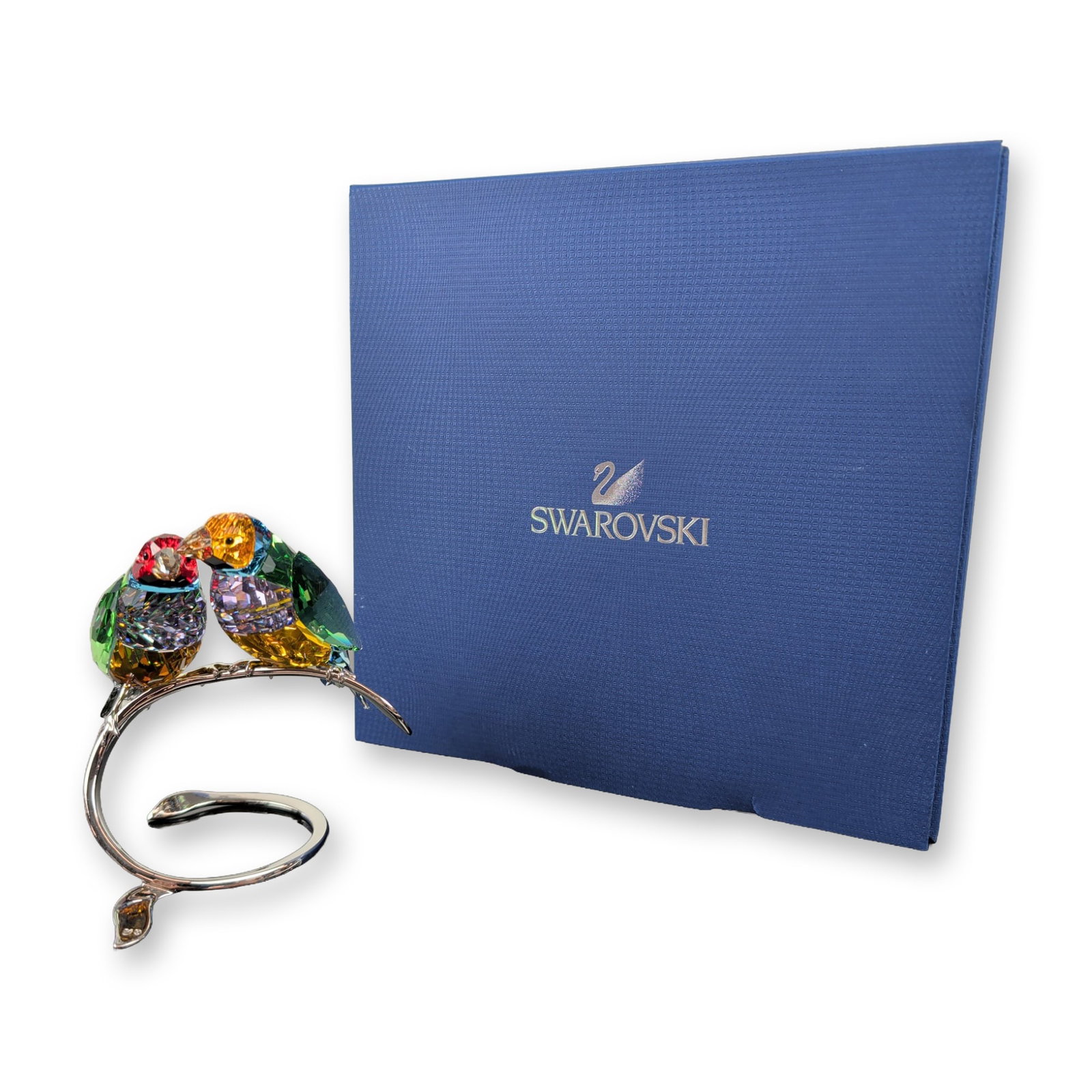 Swarovski Crystal Paradise Birds Figurine, Gouldian Finches Peridot: Peridot showcases a stunning pair of birds crafted from faceted, multi-colored crystals in vibrant shades of green, violet, amber, and red. They are elegantly perched on a silver-toned metal branch wi
