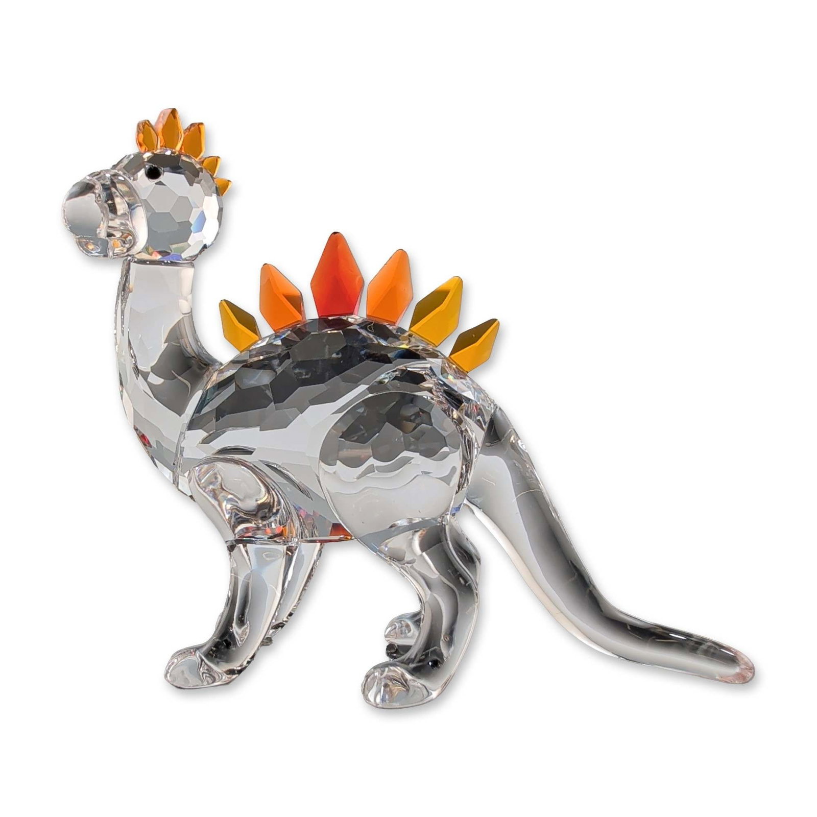 Swarovski Crystal Dino Dinosaur Figurine: Swarovski Dino the dinosaur figurine in faceted lead crystal, featuring a clear crystal body with smooth legs and tail. The figure is accented with faceted plates along the back in a gradient of yello