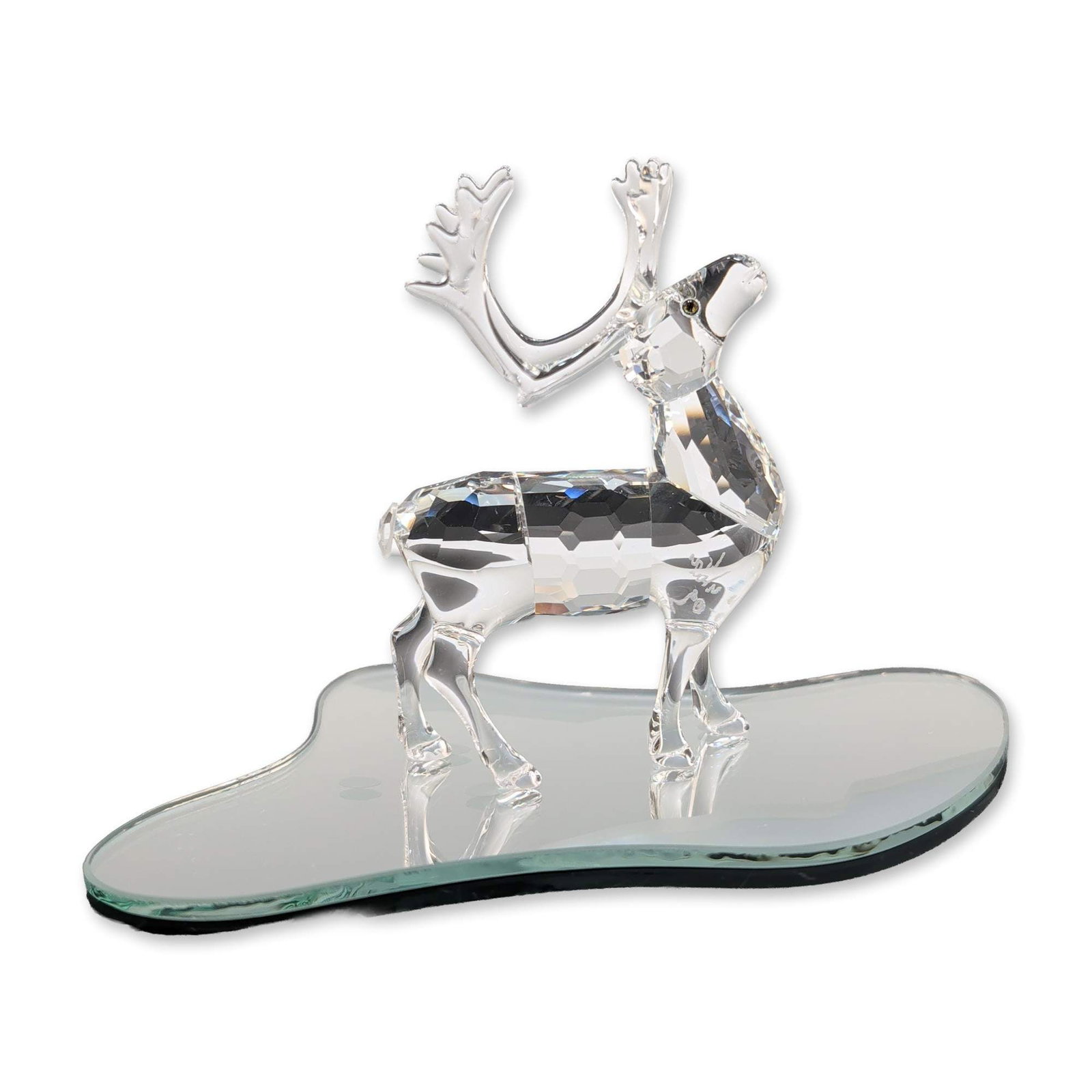 Swarovski Signed Faceted Crystal Reindeer Figurine: Swarovski Silver Crystal. Reindeer figurine in faceted lead crystal, featuring a standing pose with large, stylized antlers and set-in eyes. Includes an etched signature near front leg. Accompanied by