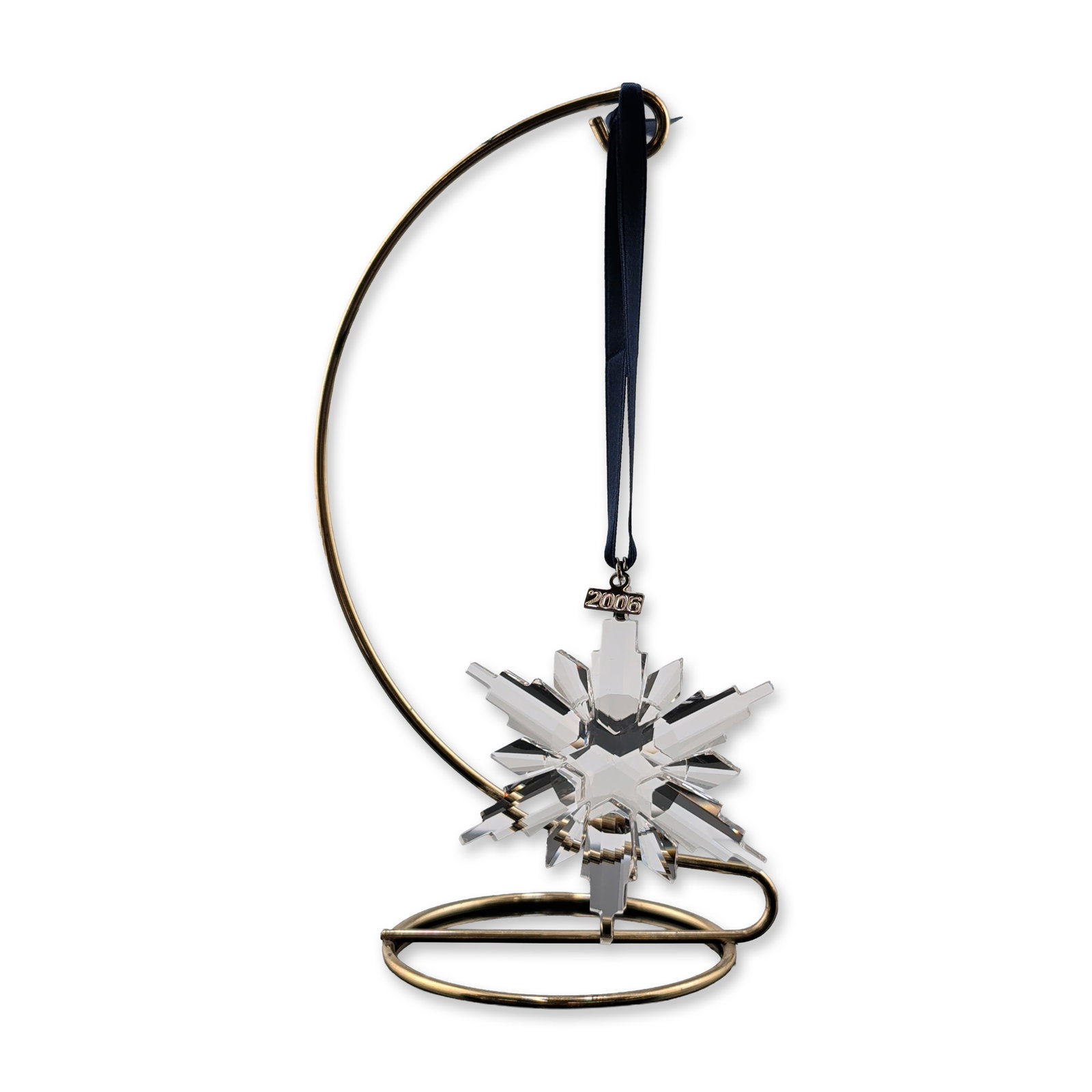 Swarovski 2006 Annual Edition Crystal Ornament: Swarovski Annual Edition 2006 Christmas ornament in faceted clear crystal, featuring a multi-pointed star design. The piece is suspended from a dark blue satin ribbon and includes a silver-toned metal