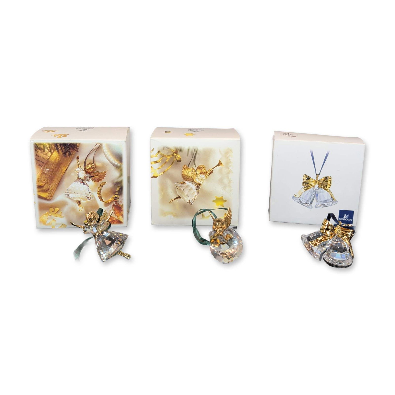 3pc Swarovski Crystal Memories Christmas Ornaments: Three Christmas ornaments from the Crystal Memories series, comprising twin bells with a polished gold-tone bow on a blue ribbon, an angel with a trumpet on a green ribbon, and a second angel figure o