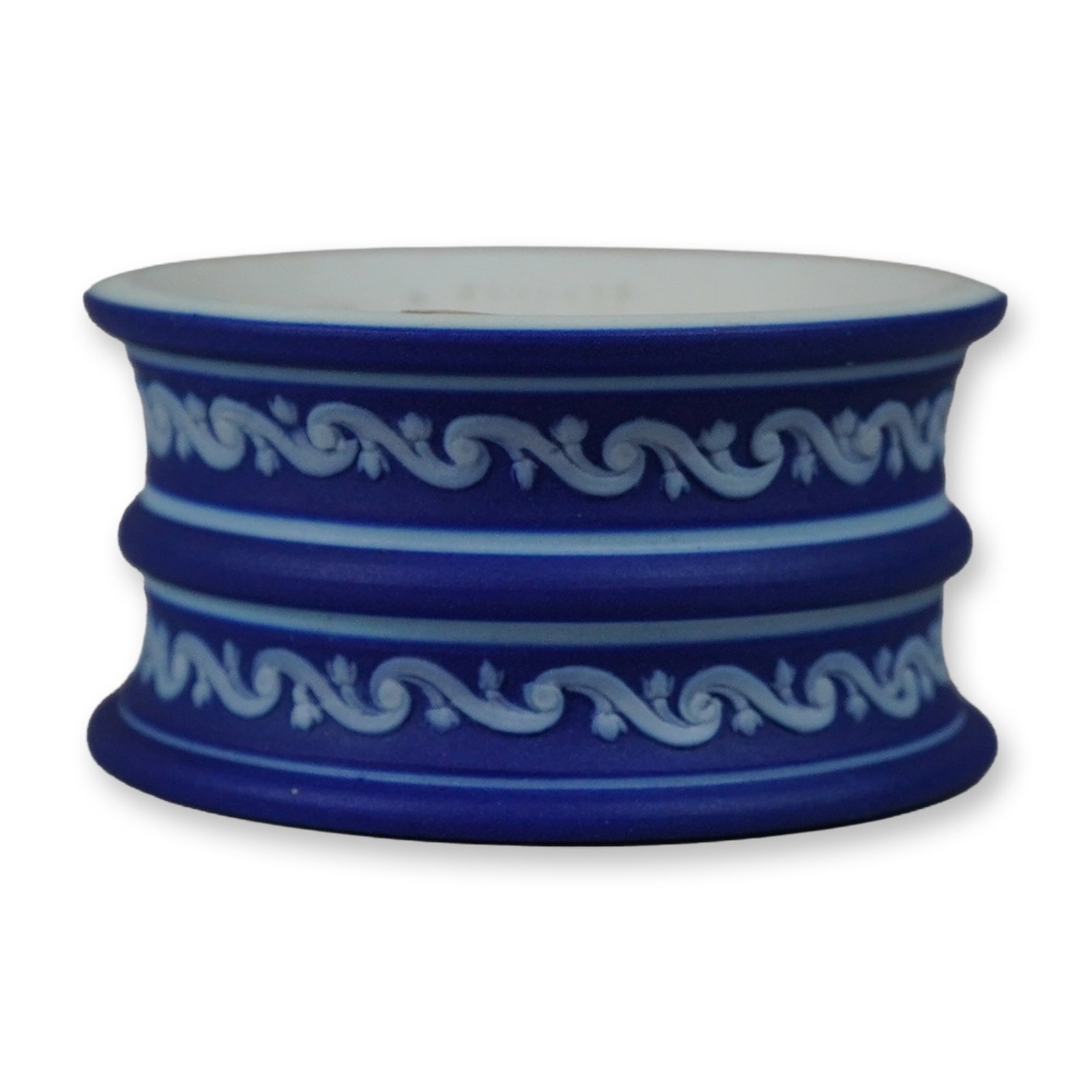 Wedgwood Cobalt Blue Jasperware Napkin Ring: This Wedgwood jasperware napkin ring features a triple-banded exterior profile. The piece is crafted from matte cobalt blue stoneware with applied white bas-relief sprigged decoration. The ornamentati