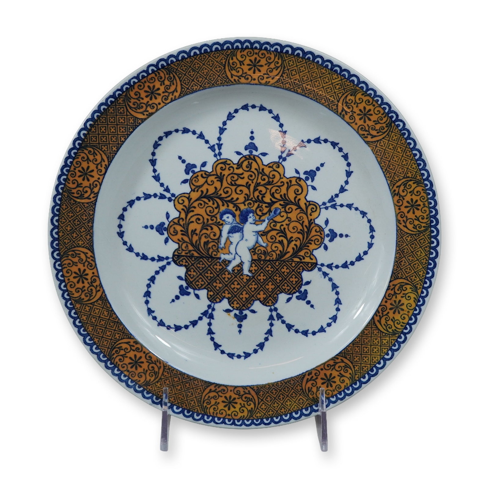 Wedgwood Metman Pattern Earthenware Plate in the Rouen Style: A Wedgwood fine earthenware plate decorated in the Metman pattern, inspired by 18th-century French Rouen faience. The decoration is executed in a color palette of cobalt blue and ochre-orange. The cen