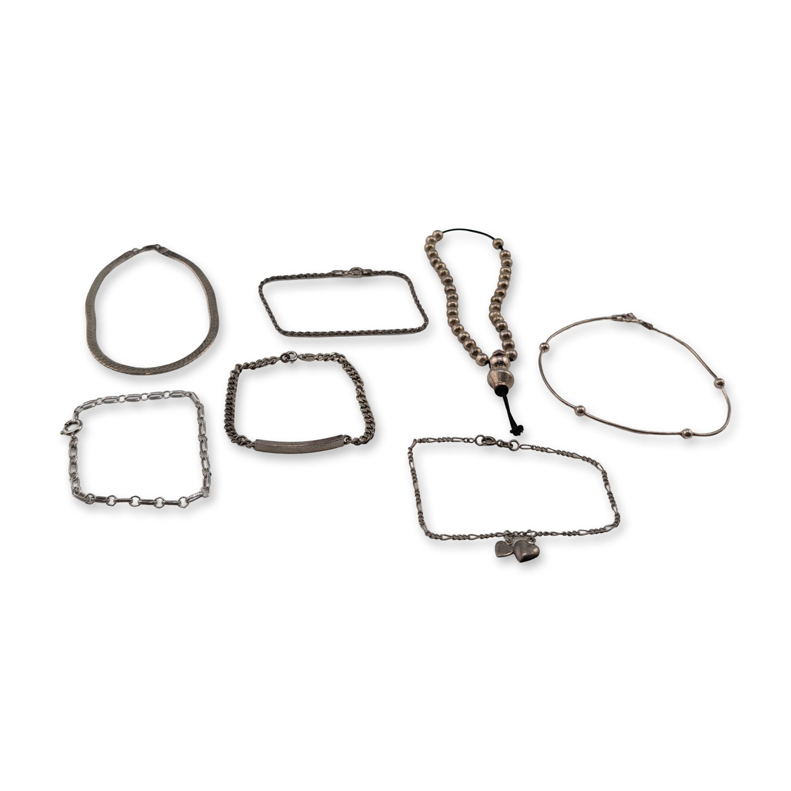 An Assortment of Seven Sterling Silver Bracelets: An assortment of seven sterling silver bracelets in various styles. The collection includes a snake chain with stationary spherical beads, and a beaded bracelet on a black cord with a sliding bead clo