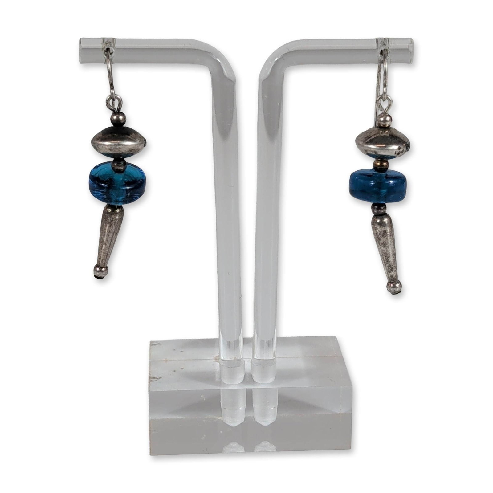 Southwestern Styles Sterling Silver Blue Glass Earrings: Southwestern style drop earrings in sterling silver and glass. Each earring features a translucent blue glass rondelle bead accented by textured lentil-shaped and tapered conical metal components. Sus