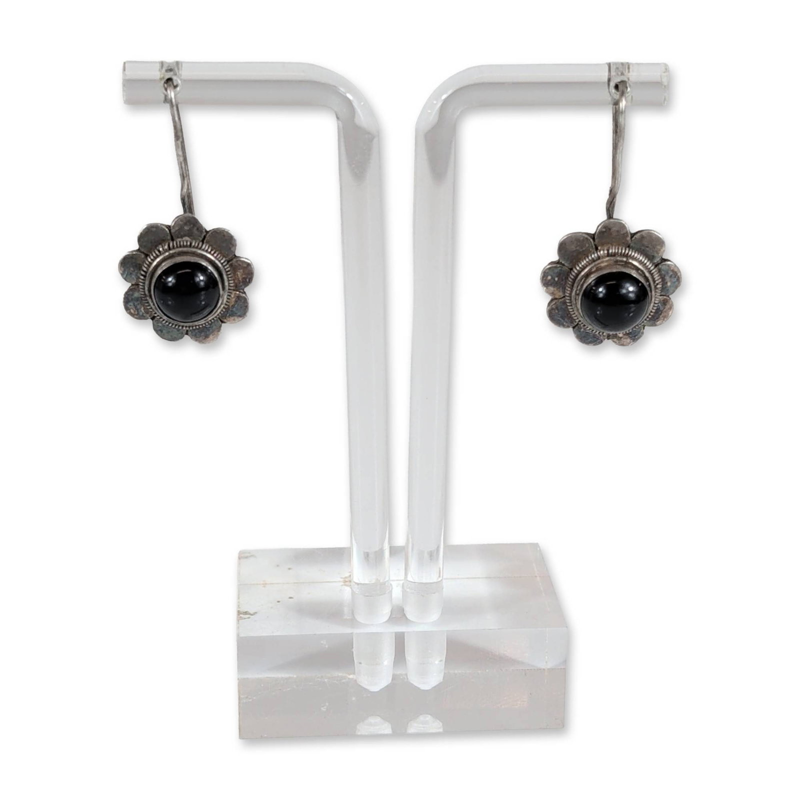 Pair of Sterling Silver Onyx Flower Earrings: Pair of sterling silver earrings in a stylized flower form, each featuring a bezel-set round black onyx cabochon center accented by a beaded wire border and scalloped edges. Pieces are fitted with fix
