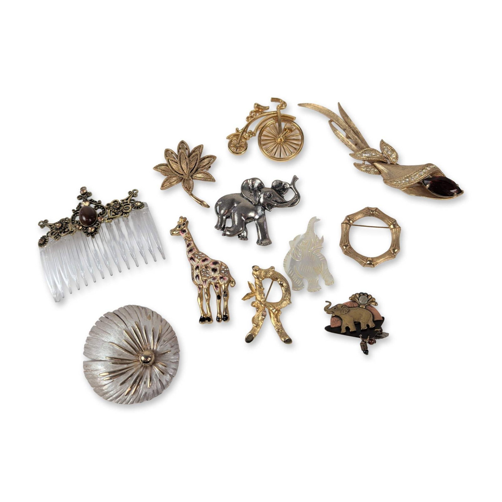 An Assortment of Eleven Vintage Costume Jewelry Pieces: An assortment of eleven vintage costume jewelry pieces, featuring ten brooches and one decorative hair comb. The collection includes a variety of motifs and materials, notably a large gold-tone calla 