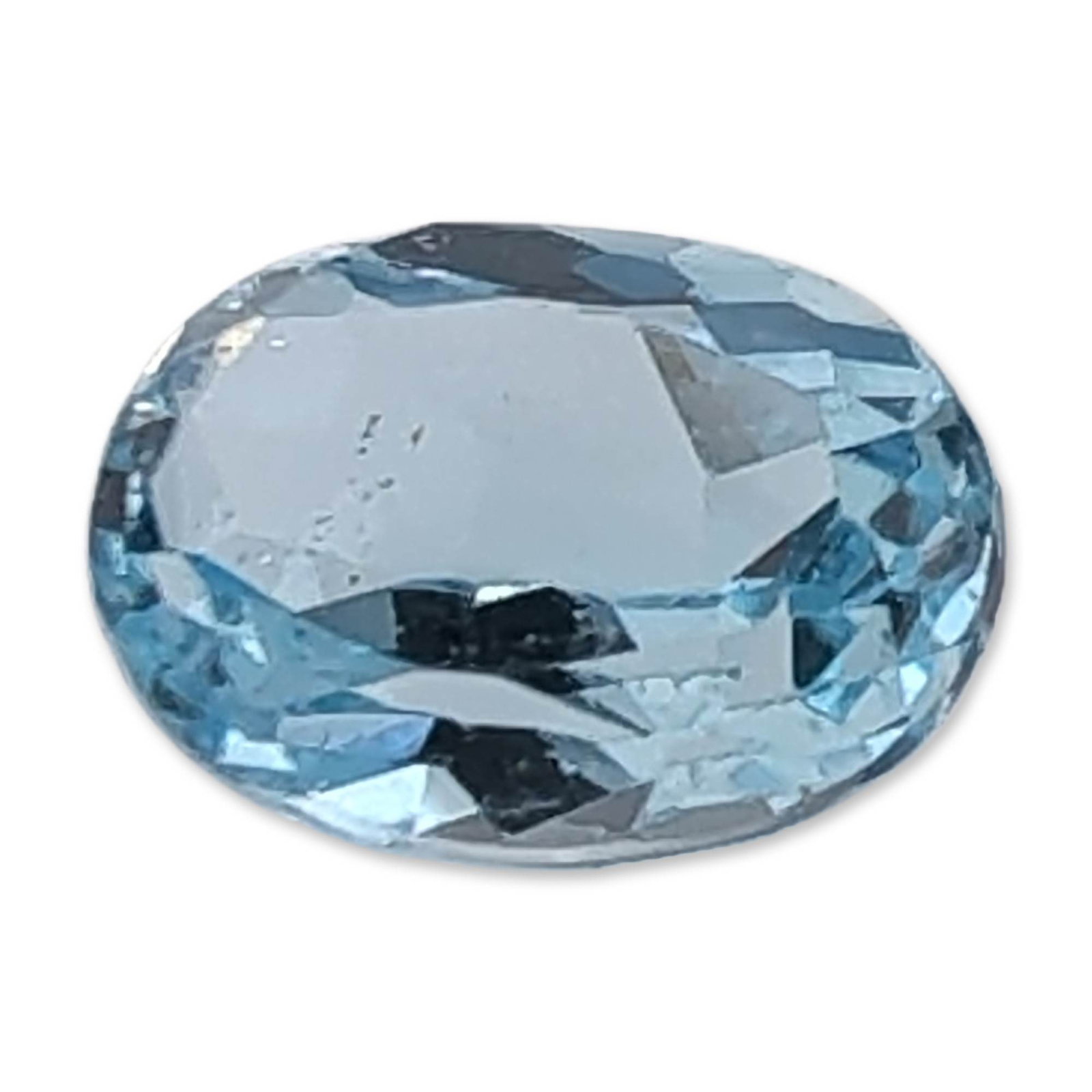 Oval Cut Pale Blue Topaz Gemstone: Single loose oval faceted Topaz gemstone featuring a pale ice blue color exhibiting transparent clarity with no apparent color zoning. It is faceted with a brilliant-style crown and a stepped pavilion