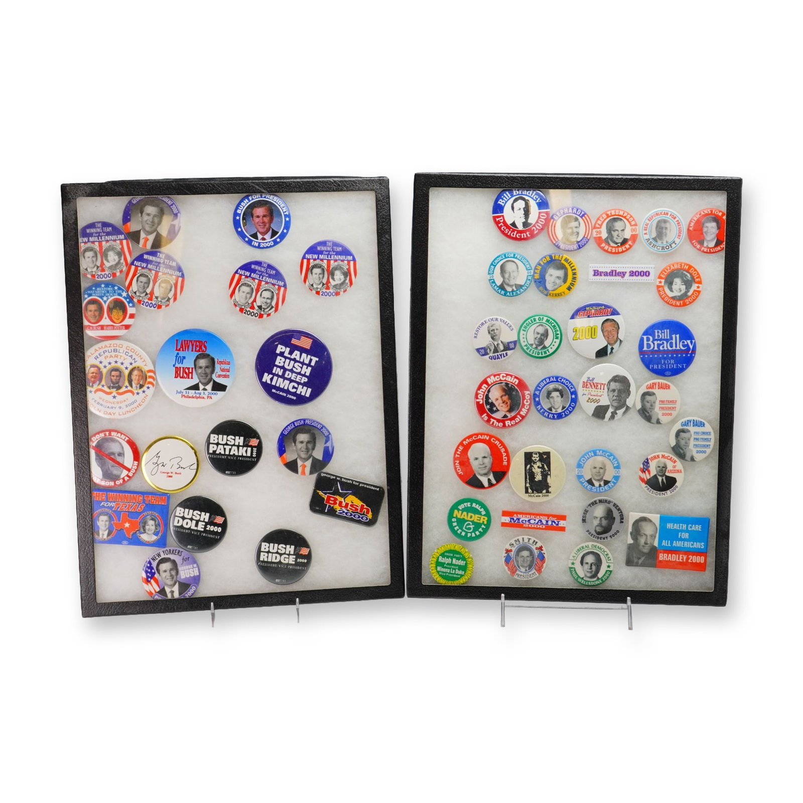 A Collection of US Political Campaign Buttons and Pins in Two Display Trays: This assortment of political memorabilia primarily focuses on the 2000 United States Presidential election. The collection is presented in two black textured display cases with foam-lined interiors. T
