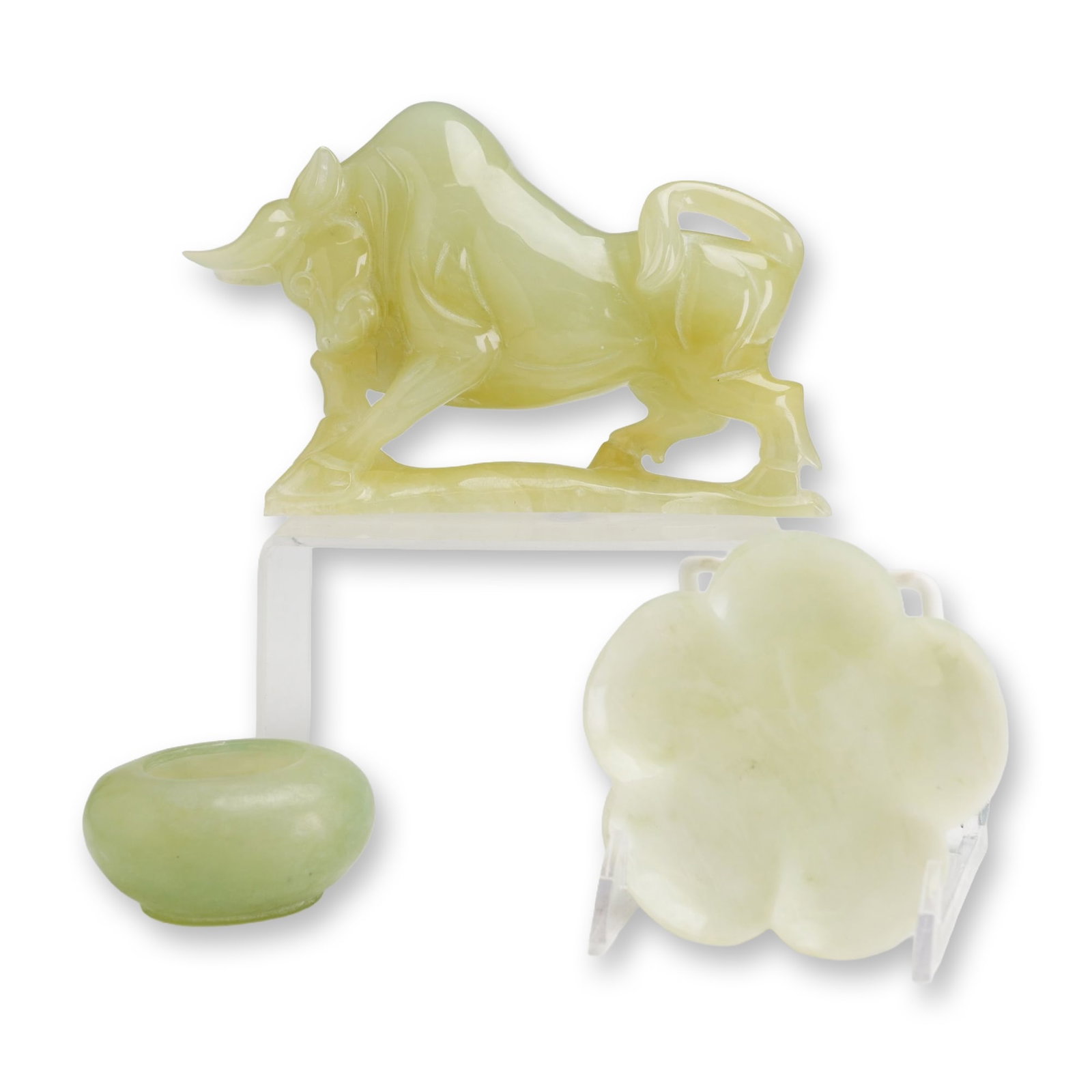 Three Chinese Style Carved Hardstone Figurine, Trinket Tray and Salt Cellar: Three Chinese style hand carved stone items, including a stylized charging bull, a foliate trinket tray, and a small oval bowl. Each piece is fashioned from varieties of pale green hardstone, likely s