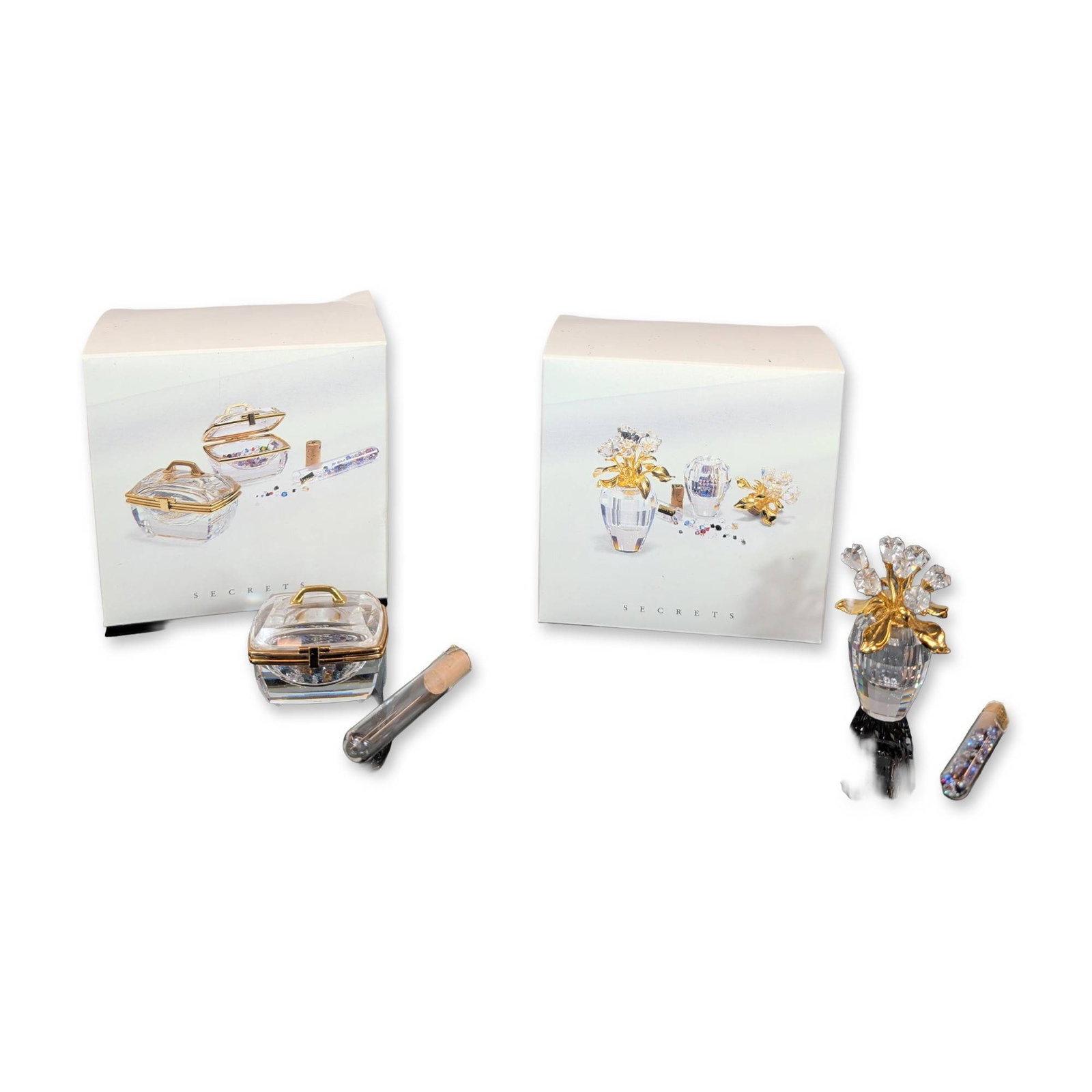 Two Swarovski Secrets Crystal Trinket Box and Vase Figurines with Crystal Vial: Two Swarovski faceted lead crystal miniatures from the Secrets collection, comprising a flower vase and a hinged jewelry box. The flower vase features a faceted crystal body with gold-toned metal stem