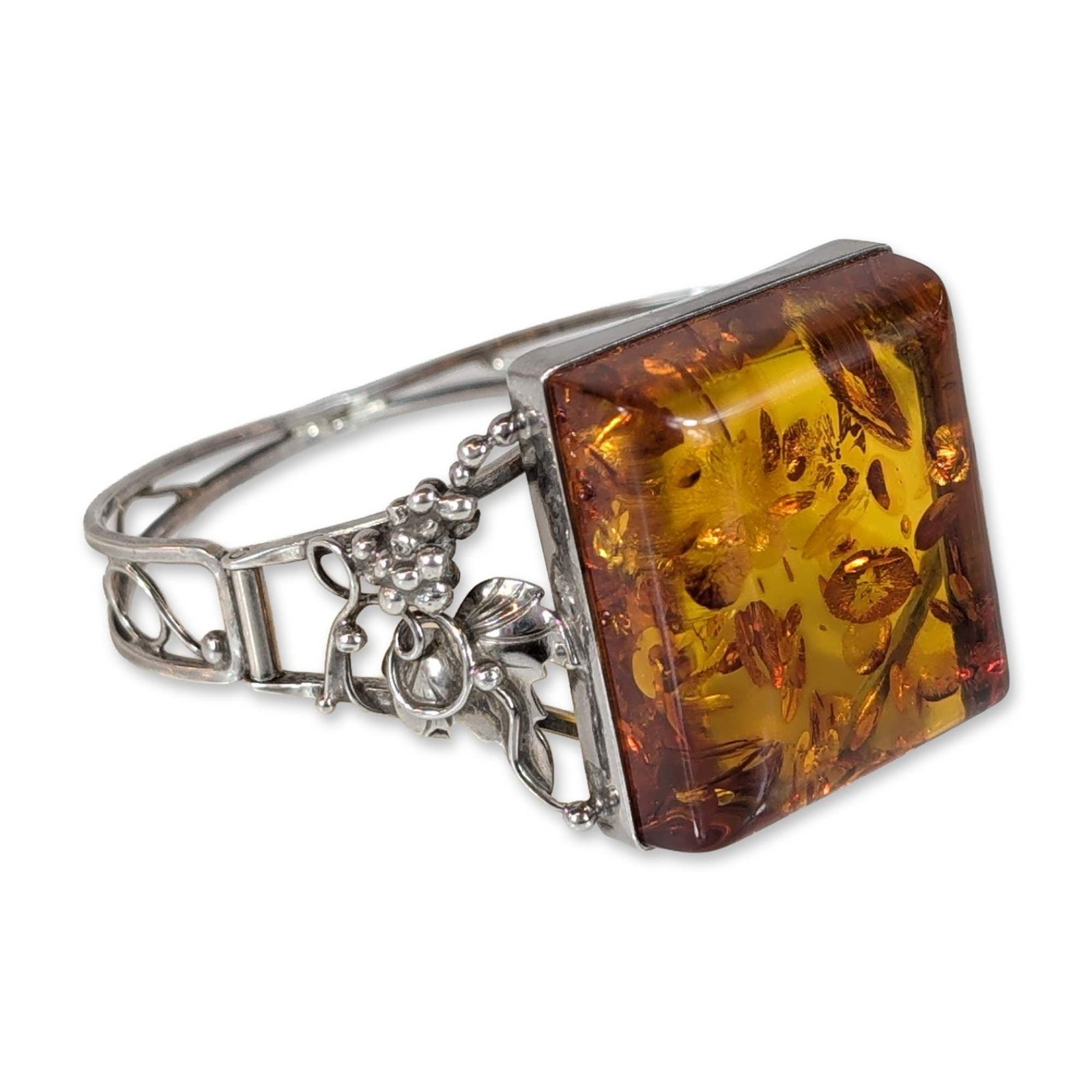 Baltic Sterling Silver and Amber Bracelet: Baltic style hinged bangle bracelet crafted in sterling silver. The centerpiece features a square-cut, cognac-colored amber cabochon with internal sun spangle inclusions, characteristic of heat-treate