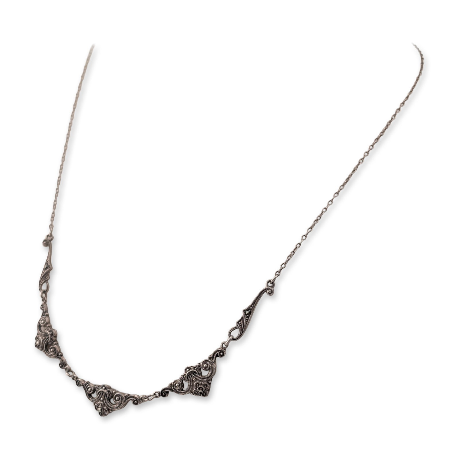 Sterling Silver and Marcasite Scrolling Filigree Style Necklace: Sterling silver and marcasite necklace in a scrolling filigree-inspired design. The central station consists of five linked openwork elements featuring foliate scrolls set with numerous round rose-cut