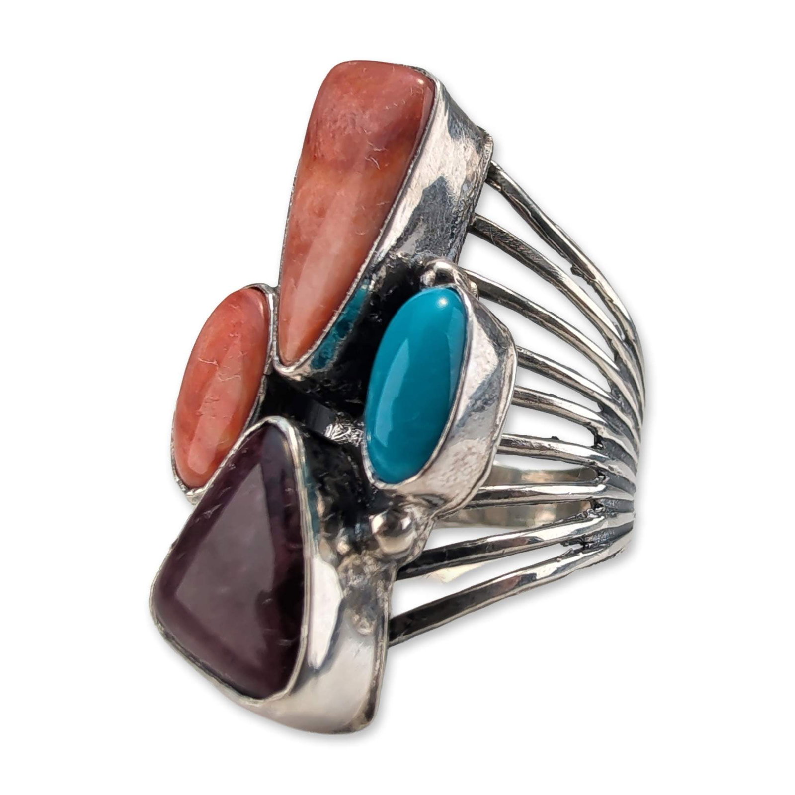 Roie Jaque Navajo Sterling Silver Multistone Ring: Roie Jaque Navajo multistone cluster ring in sterling silver, featuring four bezel-set stones comprising a triangular sugilite, two spiny oyster shell cabochons, and an oval turquoise. The cluster is