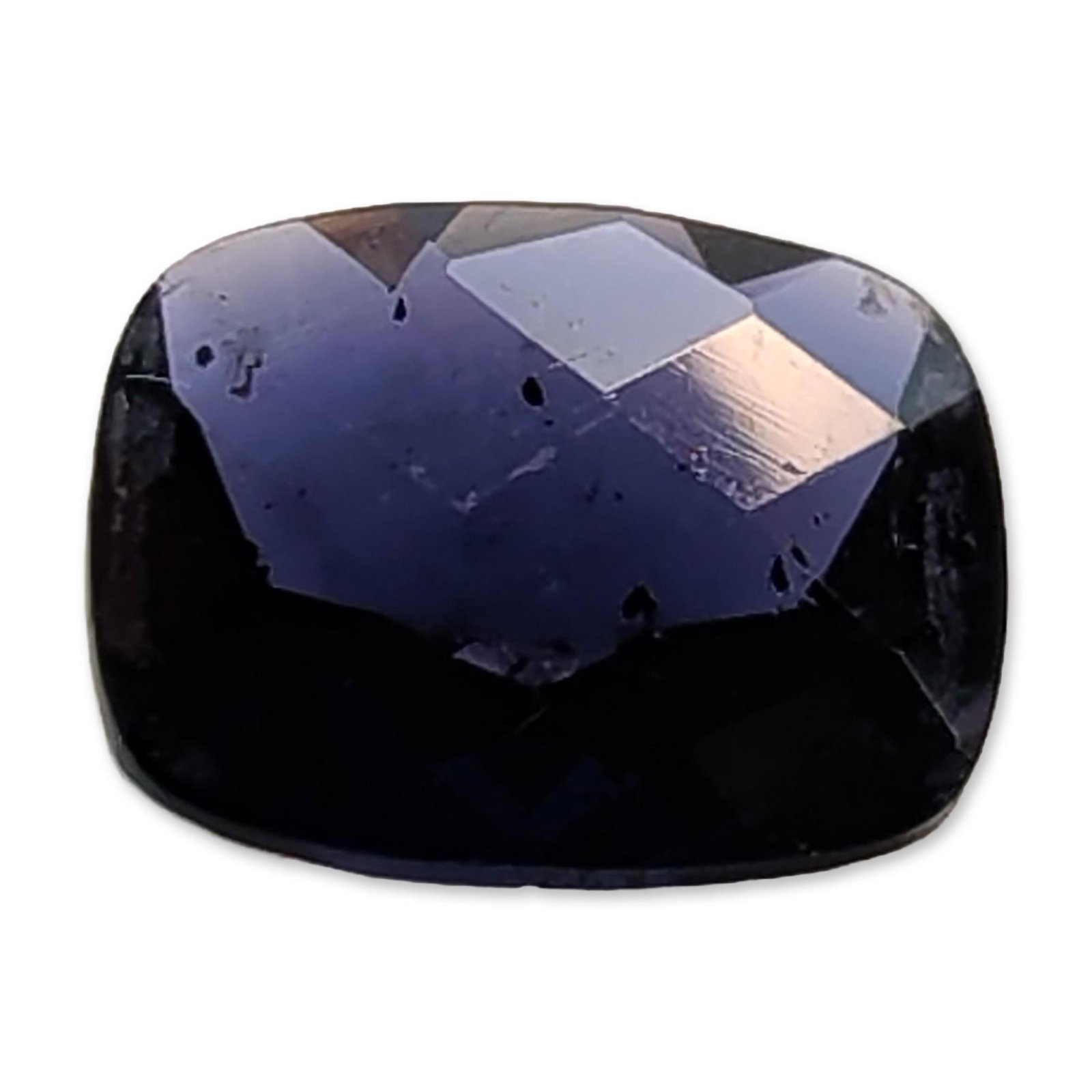 Cushion Cut Deep Violet Blue Iolite Gemstone: Loose faceted Iolite gemstone.The stone exhibits a deep violet-blue hue with significant saturation, appearing near-black in low-light conditions. Features visible internal inclusions including
