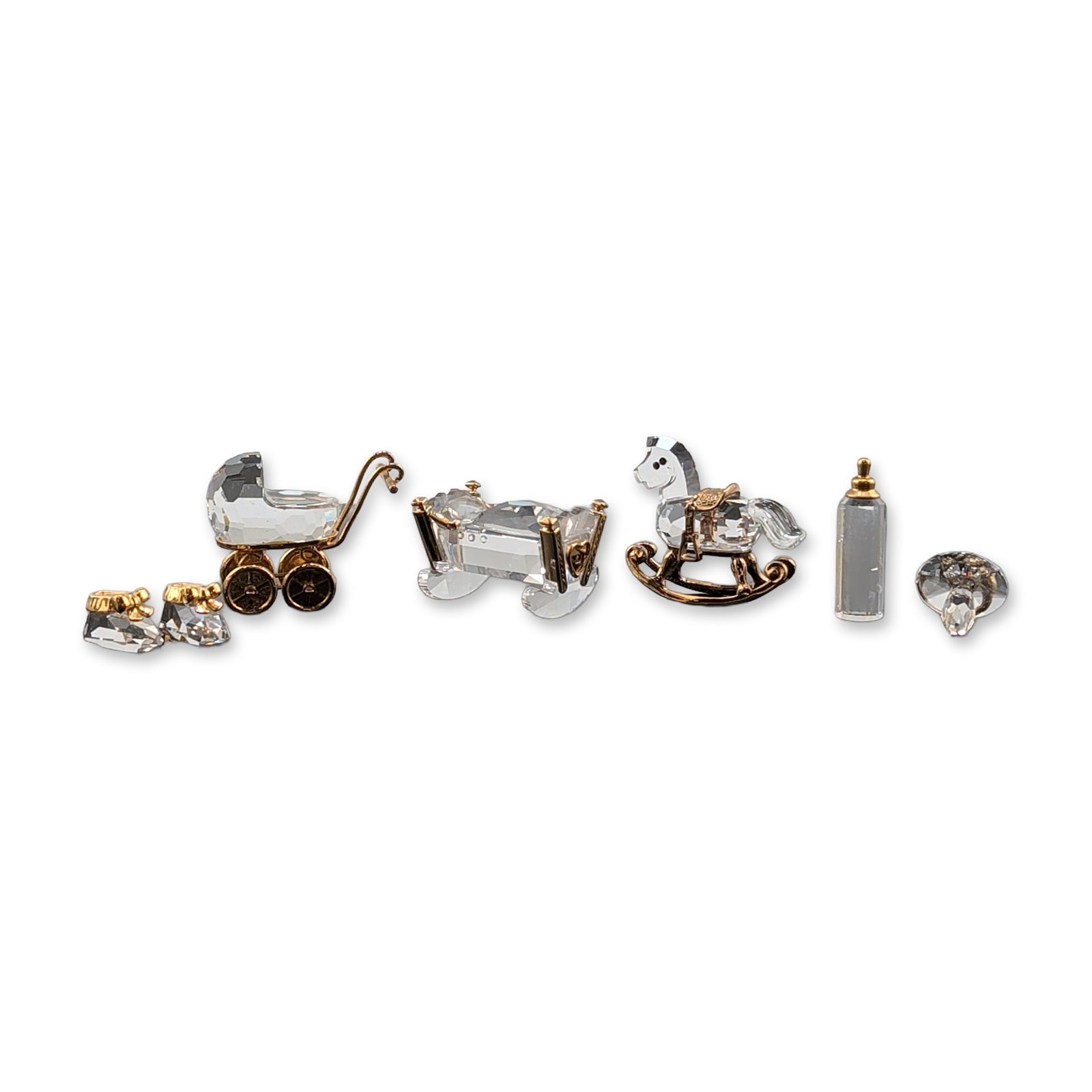 6pc Swarovski Crystal Memories Collection of Miniature Figurines: Swarovski Crystal Memories collection of miniature faceted clear crystal figurines with gold-tone metal accents. The assortment features nursery-themed objects including a rocking horse, a baby carria