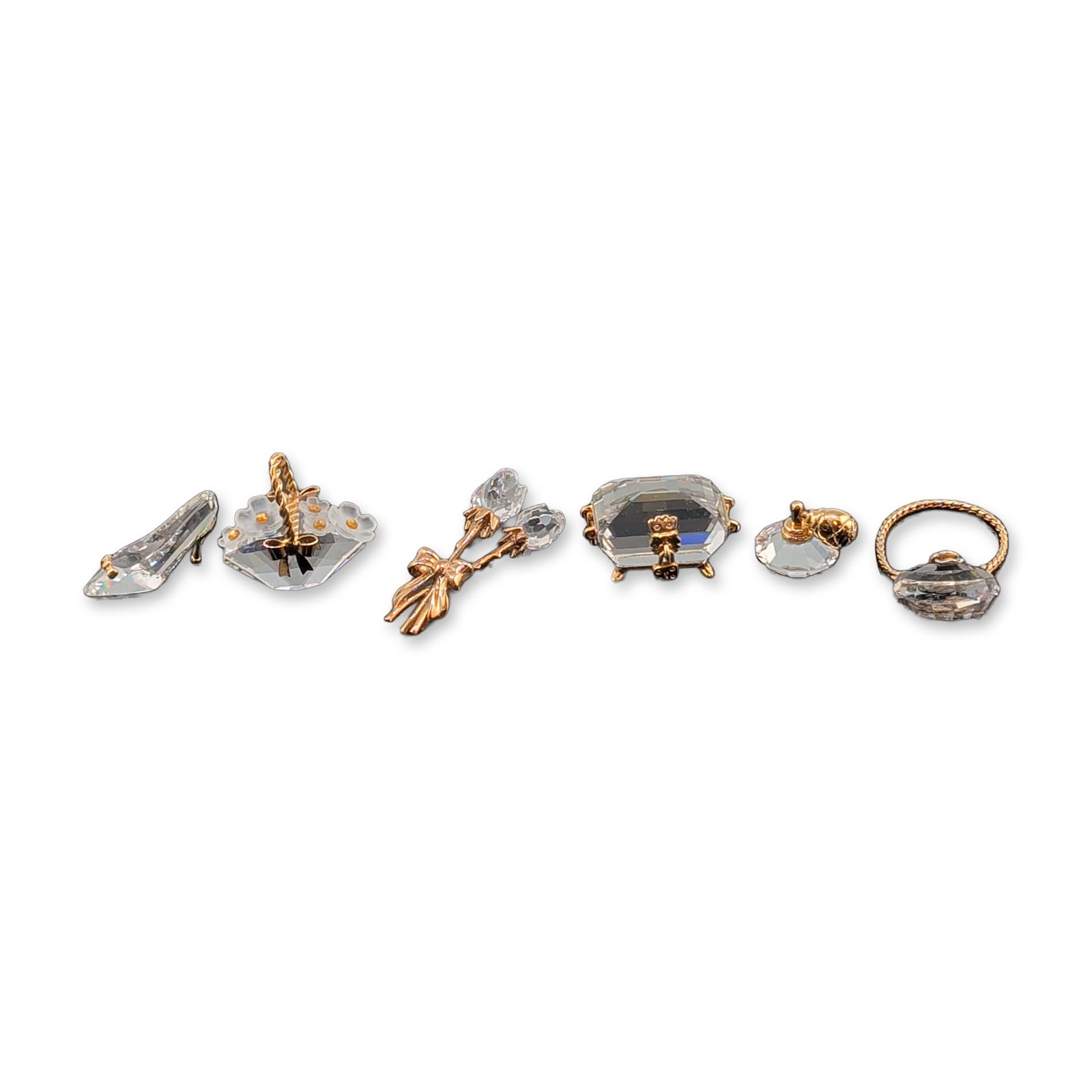 6pc Swarovski Crystal Memories Gold-Tone and Crystal Figurines: Swarovski Crystal Memories collection. Group of six miniature figurines in faceted clear crystal with gold-tone metal accents. The assortment includes a treasure chest, a flower bouquet, a high-heeled