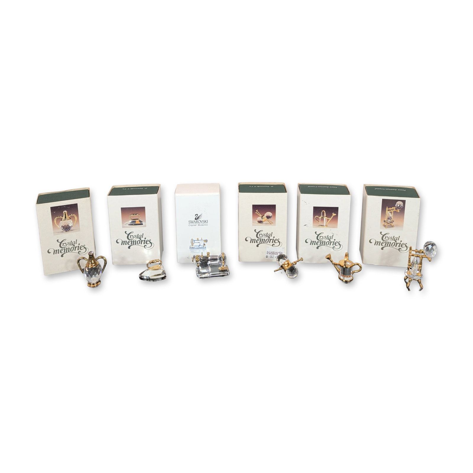 Collection of Six Swarovski Crystal Memories Miniatures: Swarovski collection of six Crystal Memories miniature figurines, each crafted from faceted clear lead crystal with gold-toned metal accents. The group includes a spinning wheel, a sewing machine, kni