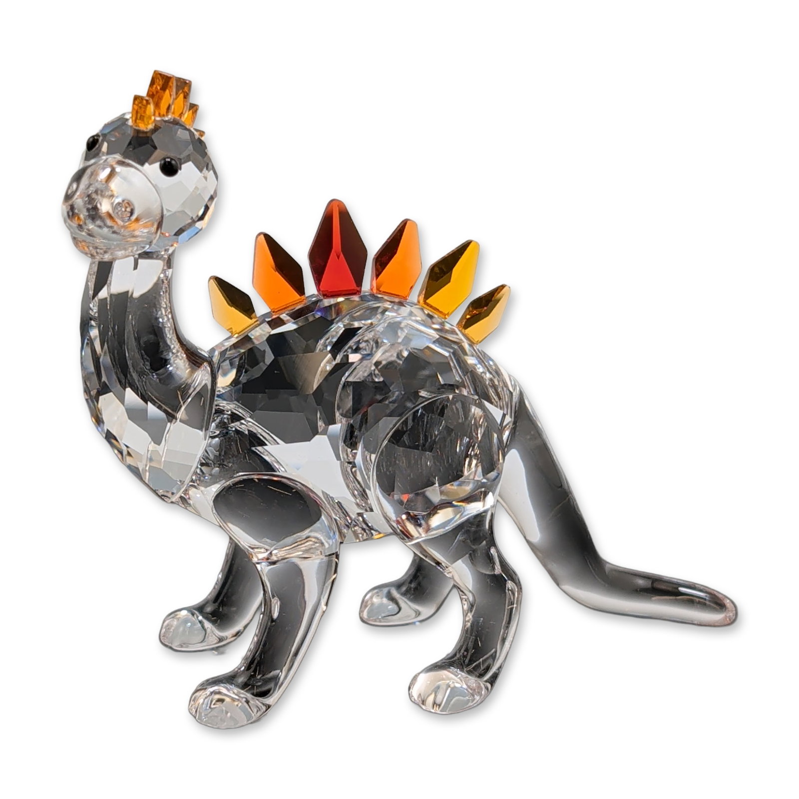 Swarovski Crystal Figurine, Dino Dinosaur: Swarovski Dino the Dinosaur figurine in faceted and smooth lead crystal. The piece features a multi-faceted body, neck, and head contrasted with smooth polished legs and an elongated curving tail. Alo