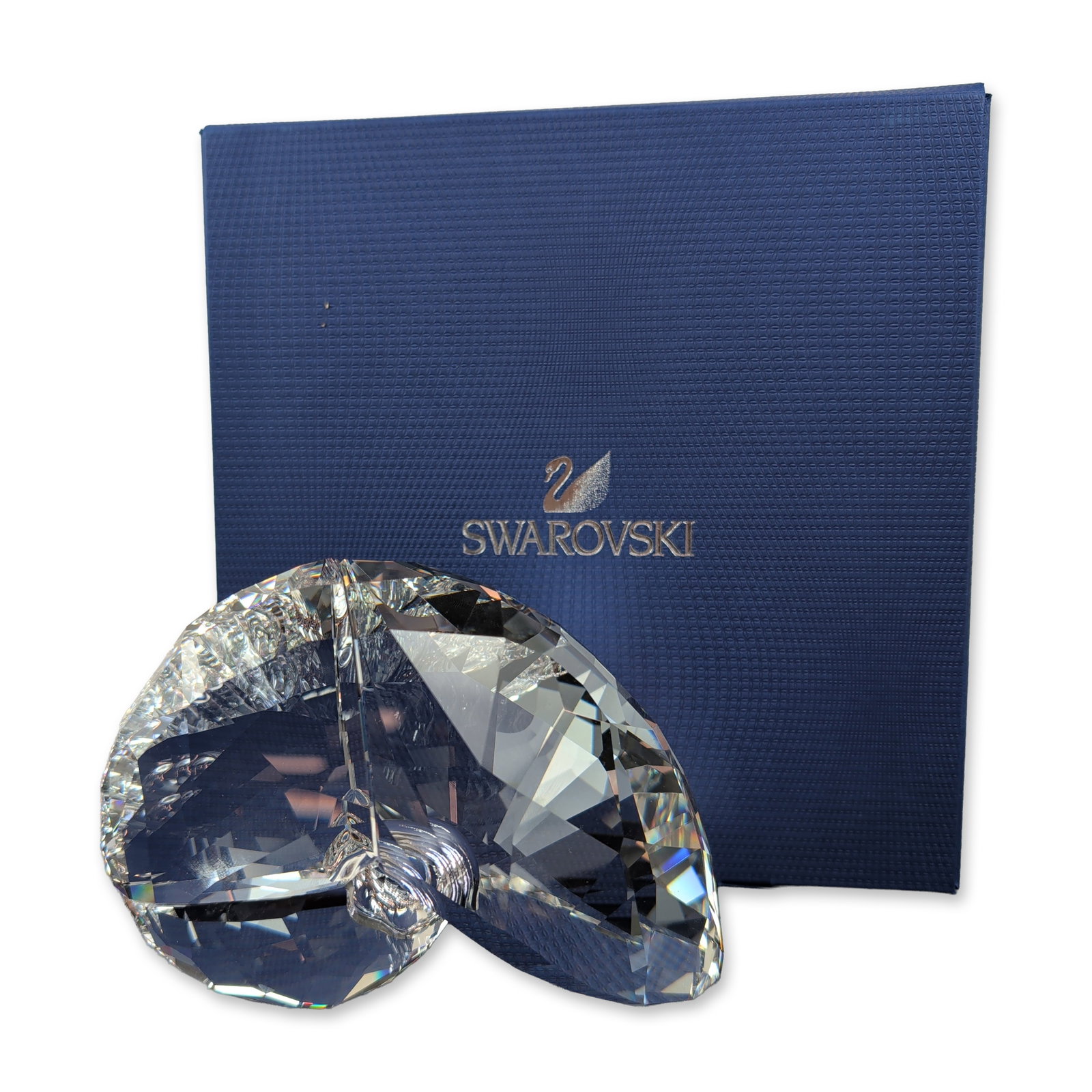 Swarovski Crystal Nautilus Shell Figurine, Signed: Swarovski. Nautilus shell figurine in faceted clear lead crystal, featuring numerous precision-cut facets. Piece bears an hand-etched signature to the outer edge. Accompanied by original blue presenta