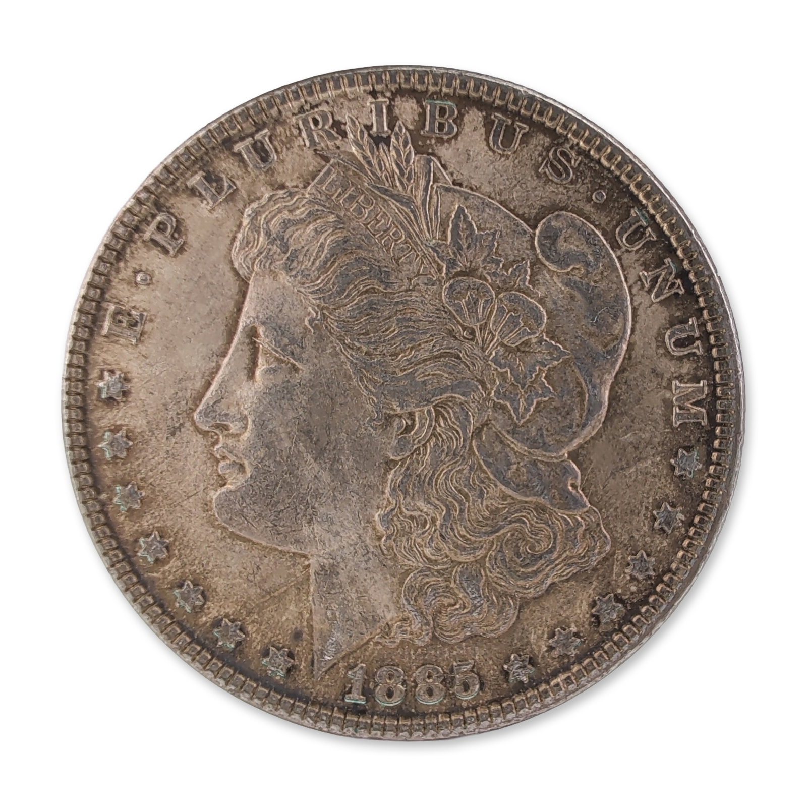 1885 US Morgan One Dollar Silver Coin, Circulated: 1885 US Morgan silver dollar struck at the Philadelphia Mint. Obverse features Liberty in profile with date and stars. Reverse depicts a heraldic eagle within a laurel wreath with no mint mark