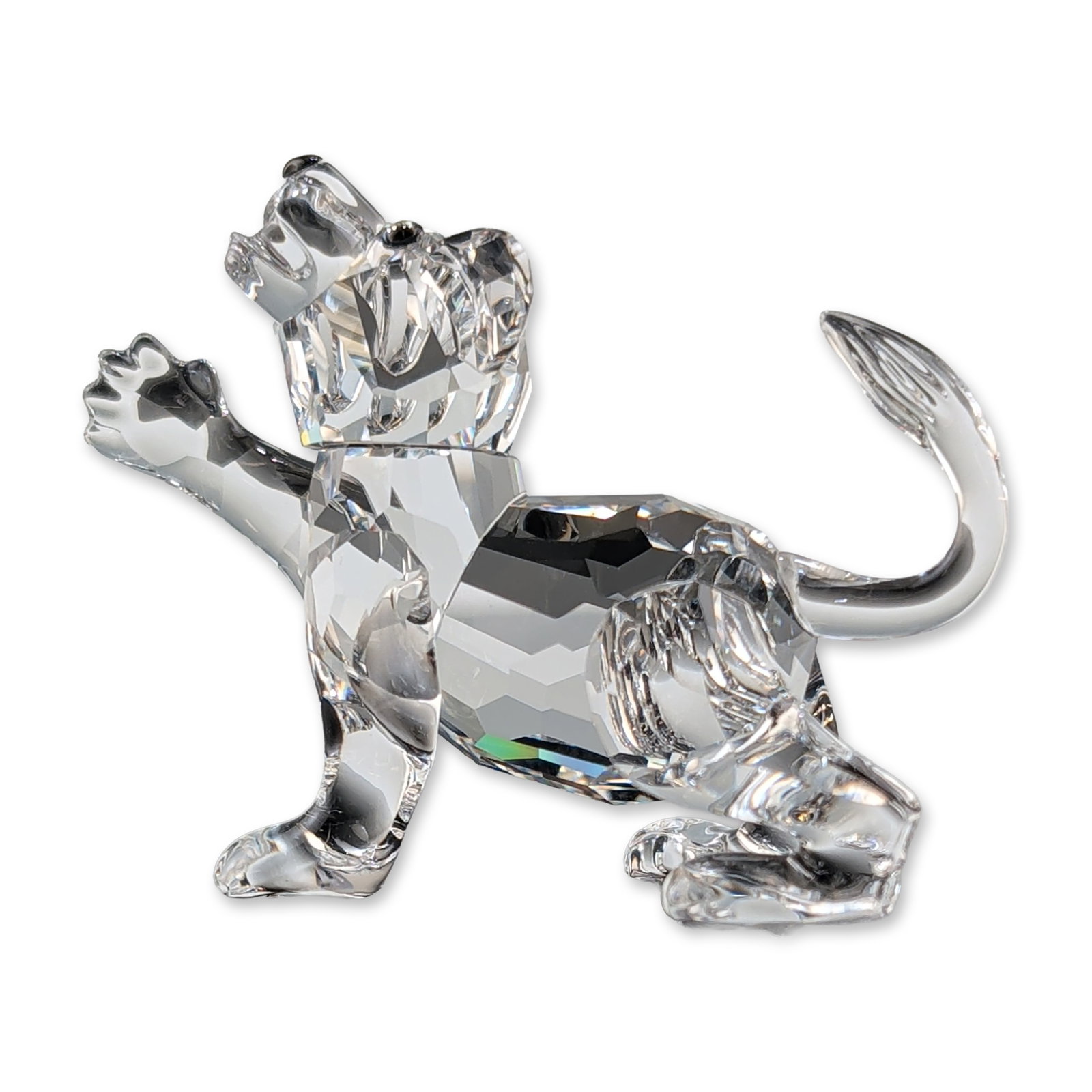 Swarovski Silver Crystal Lion Cub Figurine: Swarovski Lion cub figurine in faceted clear lead crystal from the African Wildlife collection. The piece is modeled in a pouncing posture with a curved tail and detailed faceted surfaces. Features an