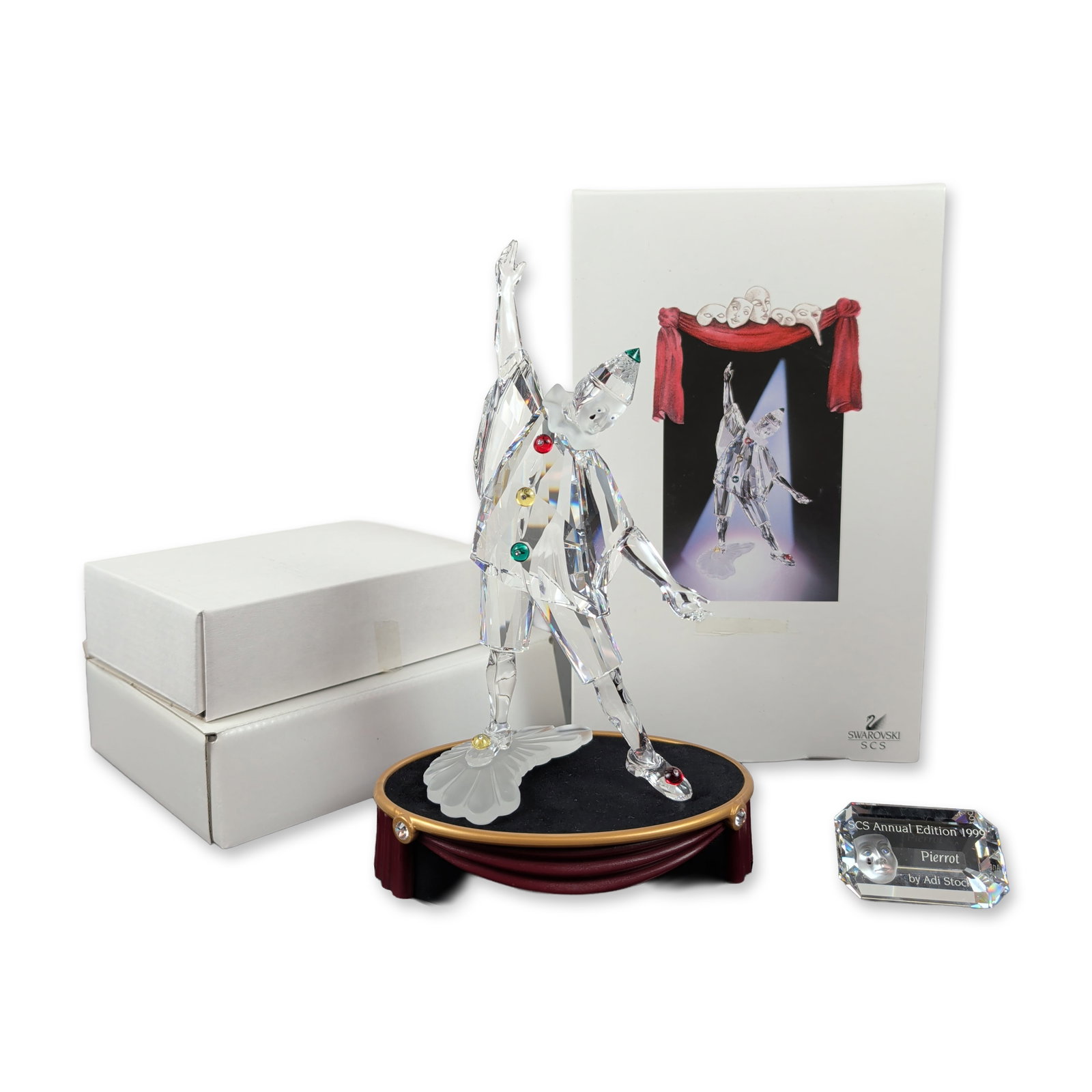 3pc Swarovski 1999 Annual Edition Figurine, Masquerade Pierrot, Title Plaque and Base: Swarovski Collectors Society Pierrot figurine in faceted clear and frosted crystal, featuring colored crystal accents and designed by Adi Stocker. Etched with Swarovski swan logo and 99 A S marks to t