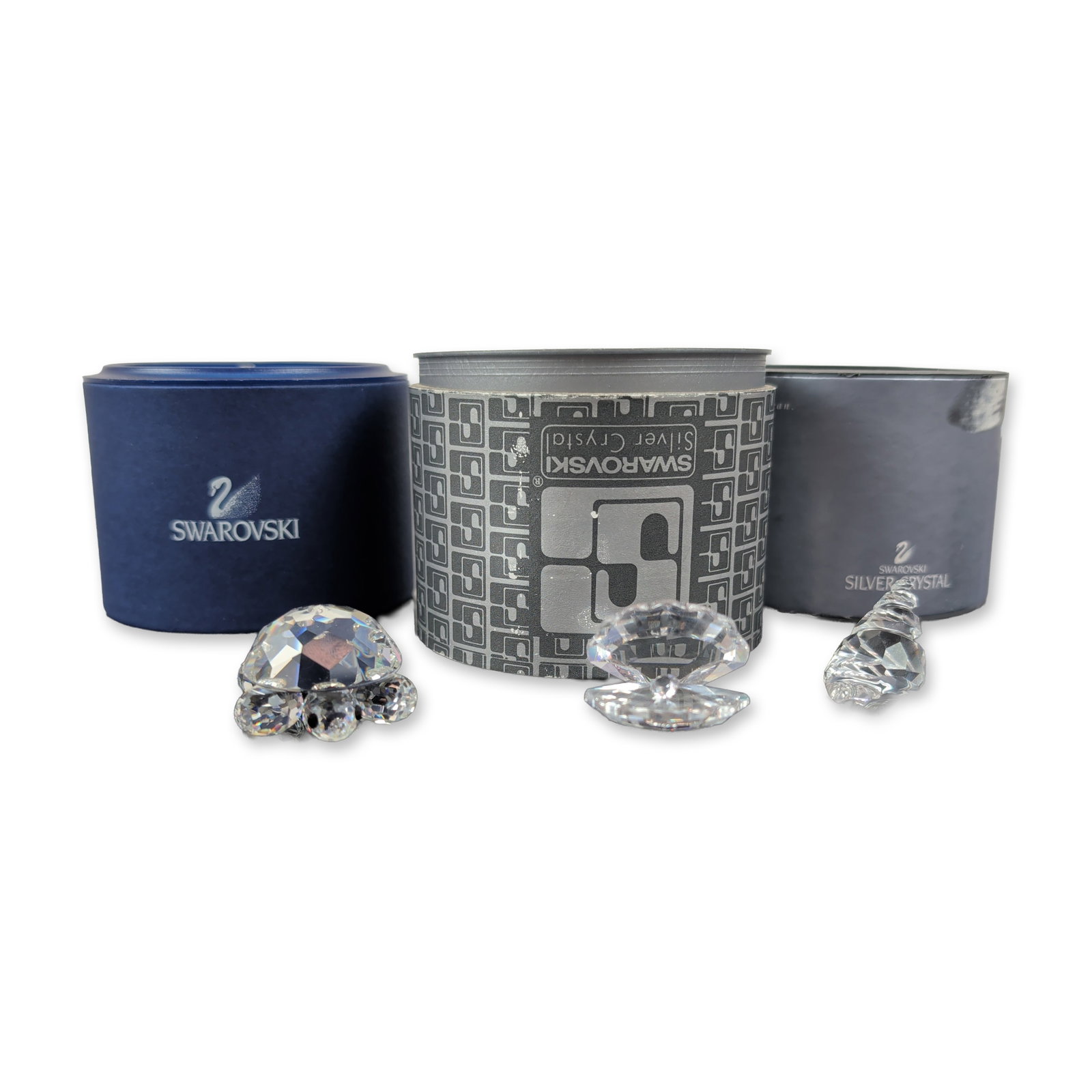 Trio of Swarovski Silver Crystal Sea Figurines: The set includes a small turtle with black faceted eyes, an open oyster shell containing a smooth crystal pearl, and a tapered spiral triton shell. Each piece exhibits precision multifaceted construct