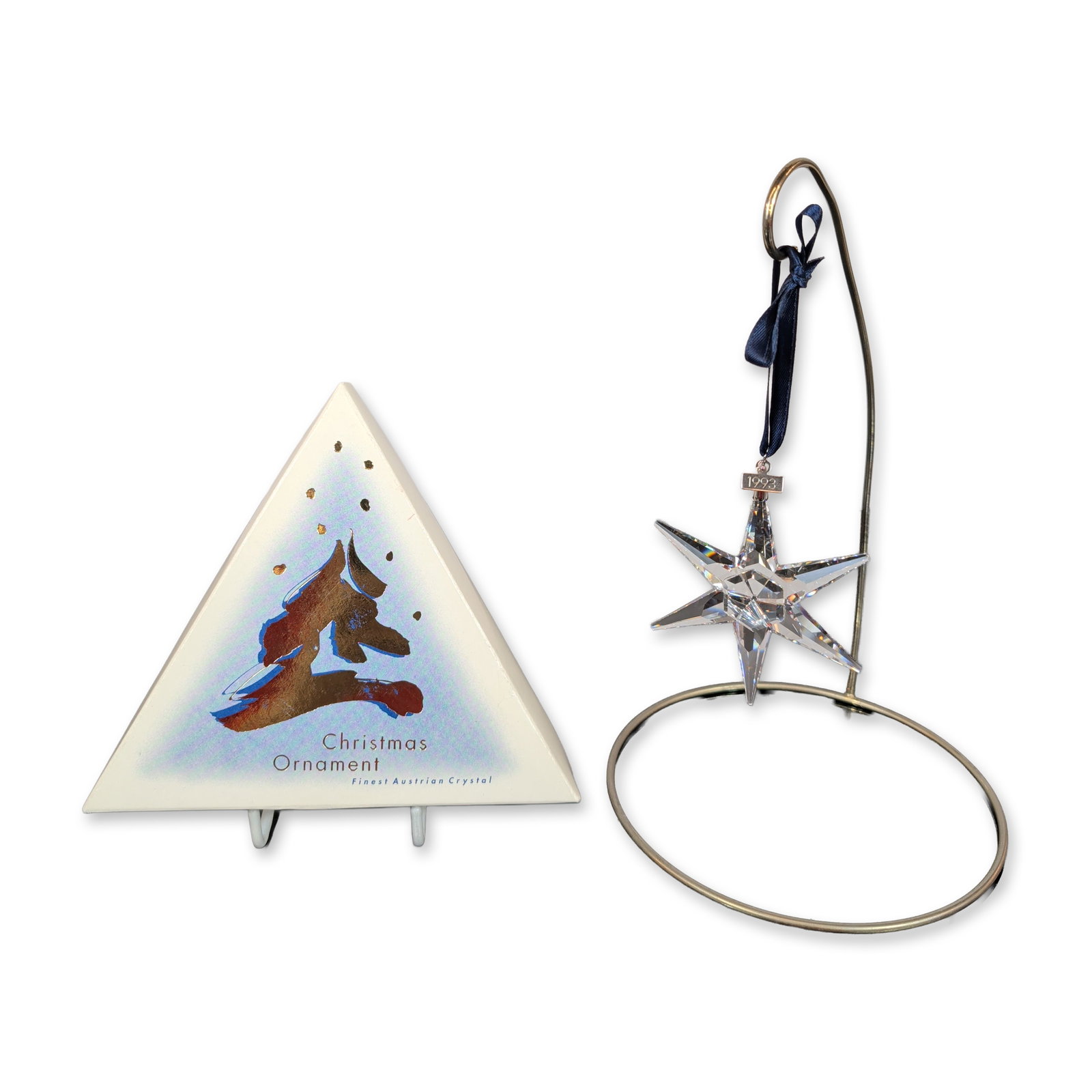 Swarovski 1993 Annual Edition Crystal Star Ornament: 1993 Annual Edition Christmas ornament in faceted clear crystal, featuring a six-pointed star design. The piece is suspended from a dark blue satin ribbon with a silver-tone metal hang tag engraved 19