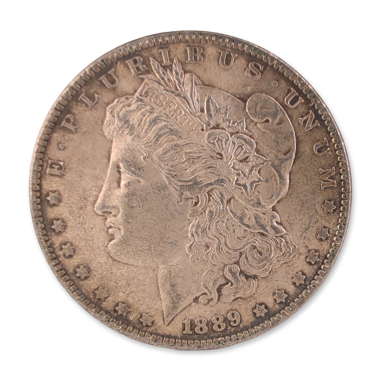 1889 US Morgan One Dollar Silver Coin, Circulated: US Philadelphia Mint. Morgan silver dollar struck in .900 fine silver. The obverse features the Liberty head design wearing a Phrygian cap with an inscribed hairband, surrounded by thirteen stars and 