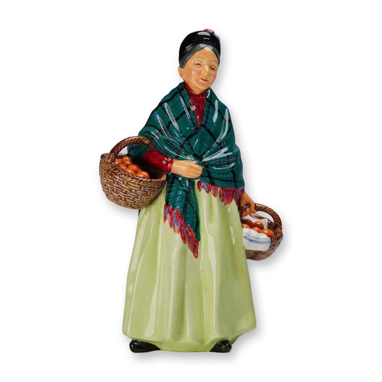 Royal Doulton Figurine, Orange Lady HN1953: This hand-painted porcelain figure depicts a woman carrying baskets filled with oranges. She wears a long pale green skirt, red blouse, and a green checked shawl with red fringe, while her dark hair i