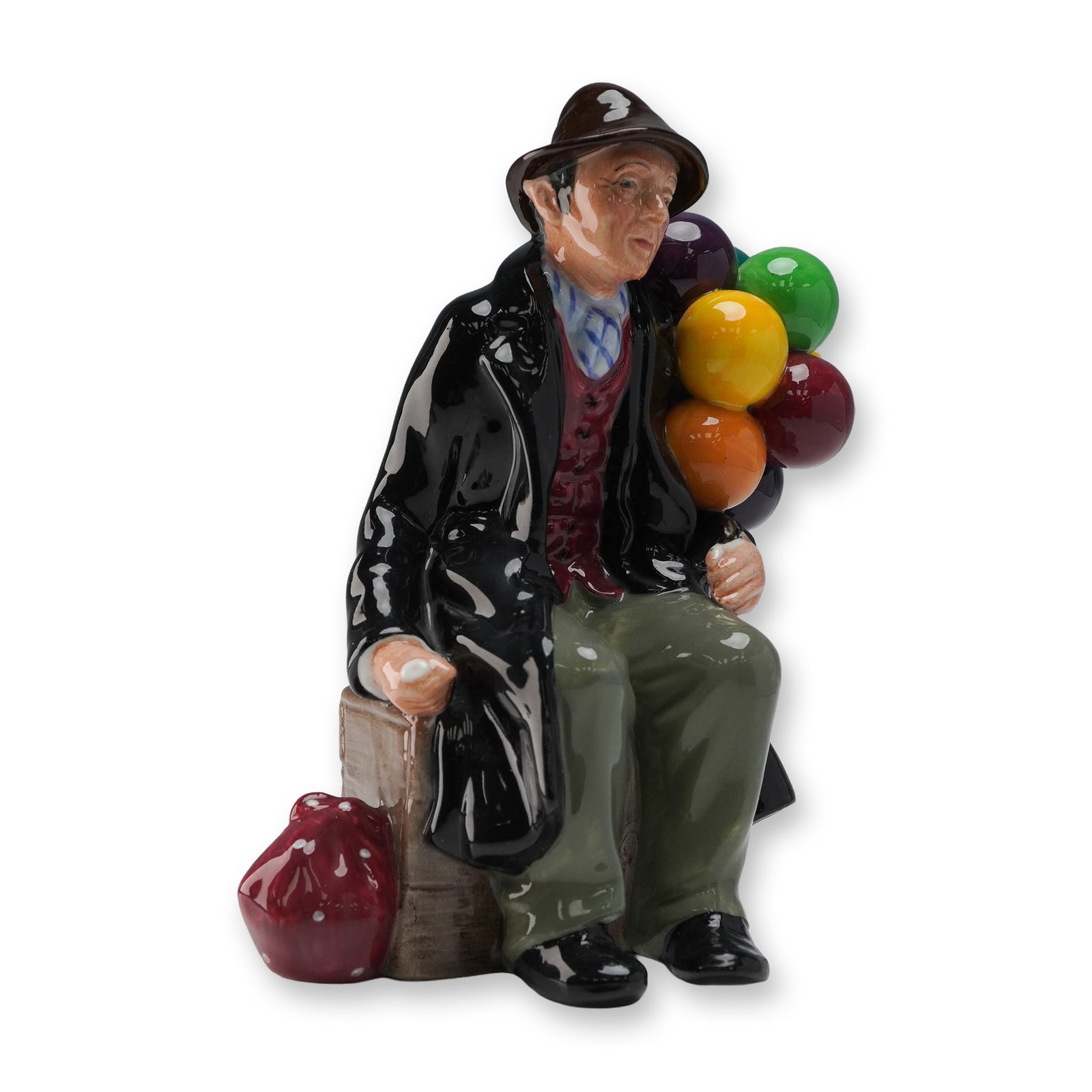 Royal Doulton Figurine, The Balloon Man HN1954: Royal Doulton figurine titled The Balloon Man, model HN1954. This beloved figure features an elderly gentleman seated on a crate with a colorful cluster of glossy balloons at his side and a red satche