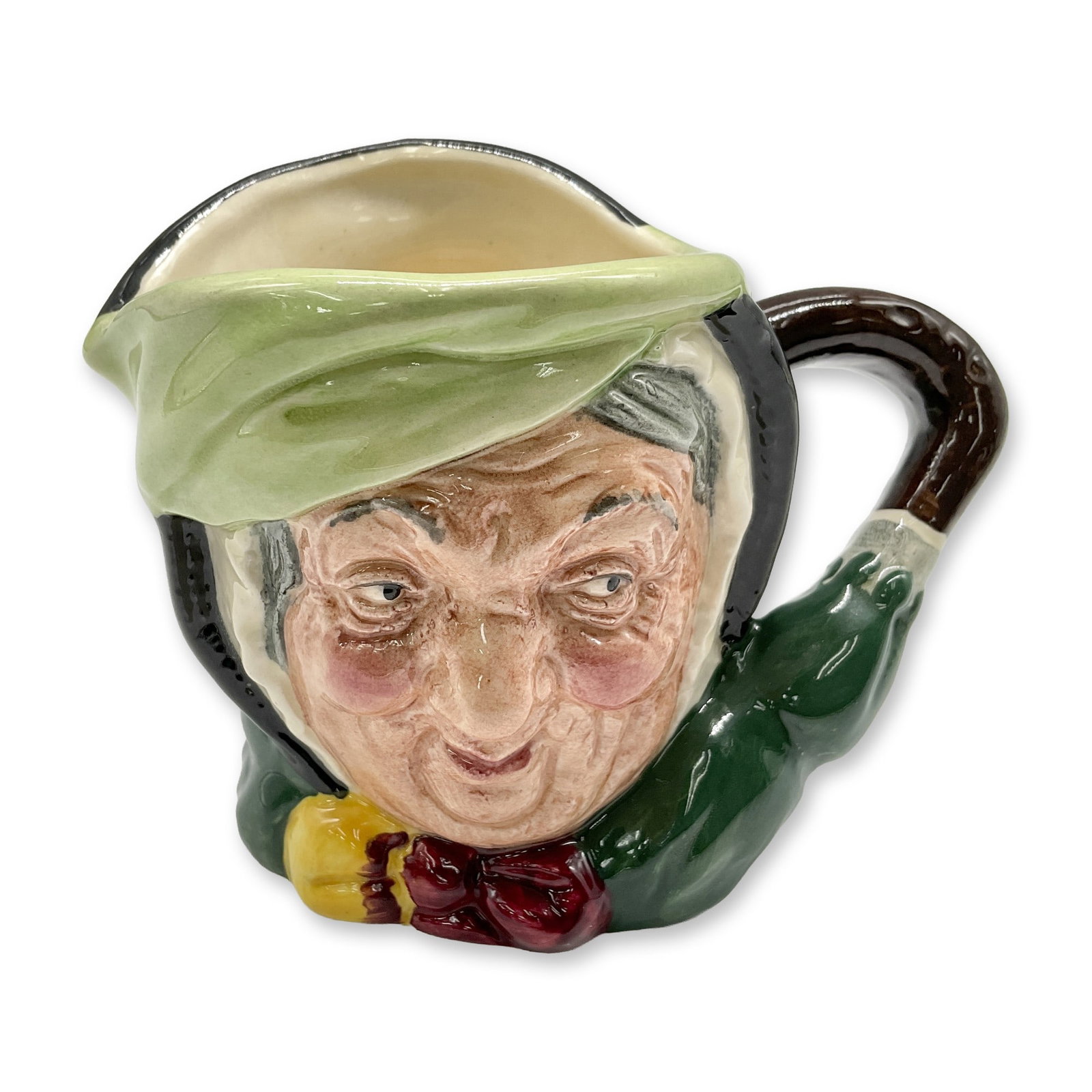 Sairey Gamp D5528 - Small - Royal Doulton Character Jug: Black hair; light green band; dark green coat; yellow and burgundy bow; green umbrella with brown handle. Royal Doulton backstamp. Artist: Leslie Harradine and Harry Fenton Dimensions: 3.25"H Date or 
